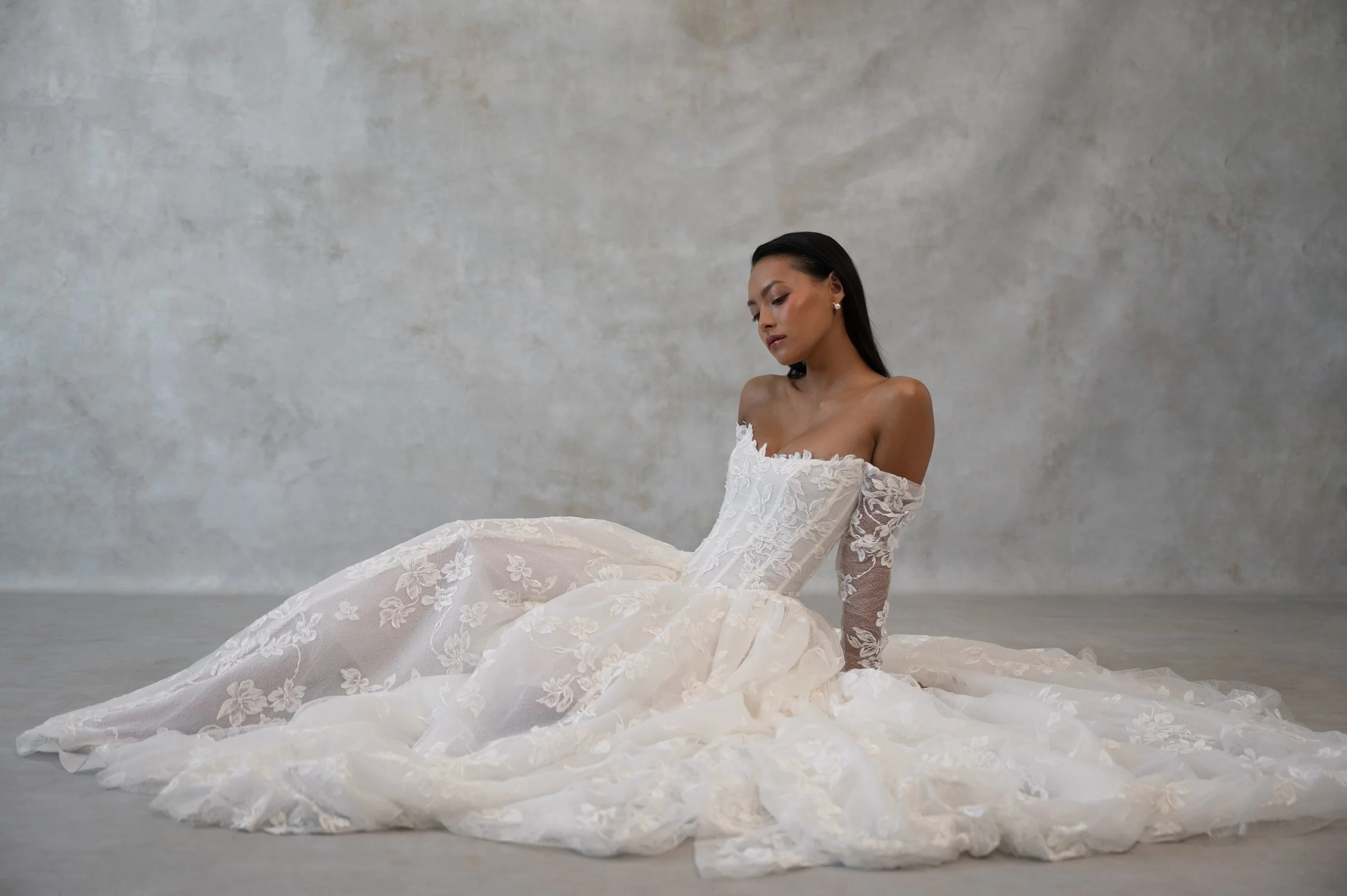 The Jenny Yoo Phoebe gown, cut in our delicately textured Isadora floral embroidery, is as modern as she is romantic. The structured Basque corset bodice leads way to a flowing gathered skirt. Detachable long sleeves lend exciting versatility.