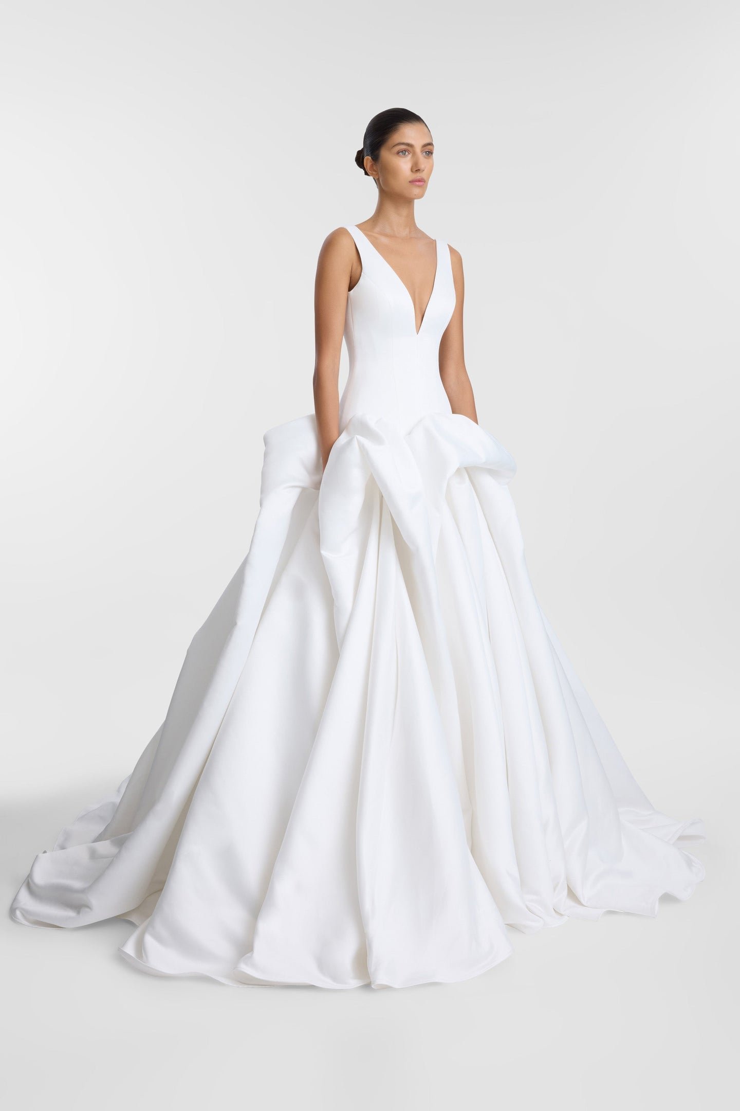Drama takes shape in KYHA Bride Bailey at Halo + Wren. A directional take on the classic ballgown, Bailey is crafted from lustrous duchess satin and defined by artfully placed, architectural draping. Sculptural folds play with light and bring dimensi