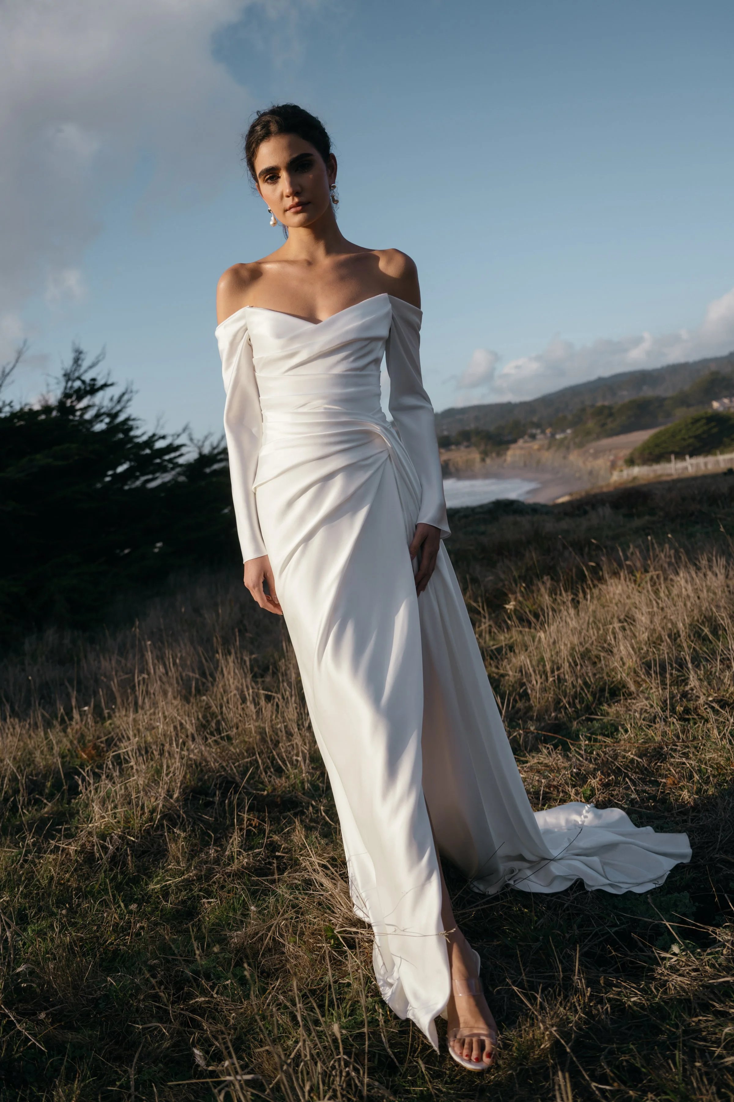 The Jenny Yoo Lana gown is a refined satin wedding dress cut in luminous Barcelona satin with elegant pleating and draping that flatters the figure, and it stands out for its versatile styling with removable long sleeves and optional sash sleeves tha