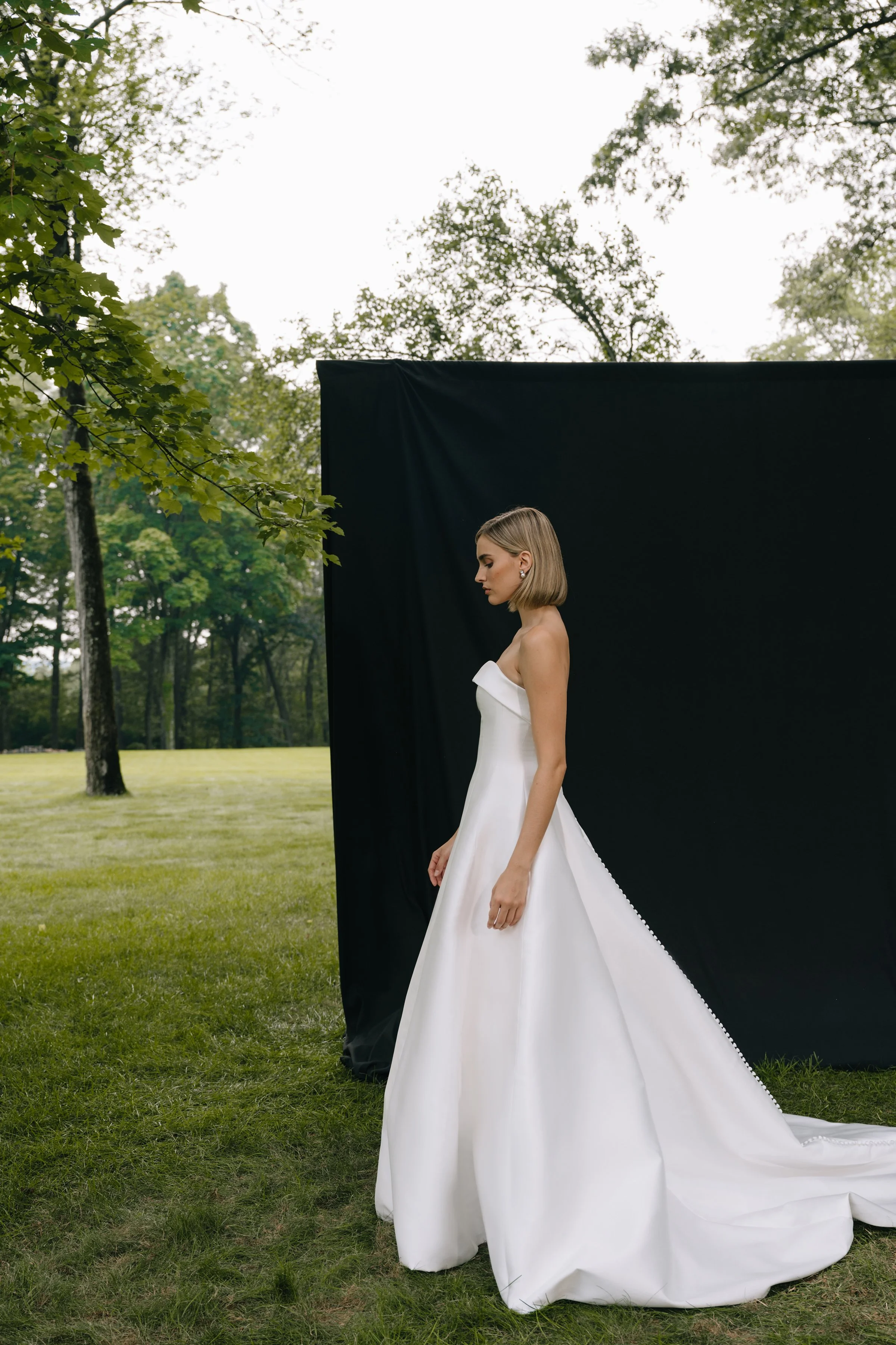 The Jenny Yoo Bridal Leah gown is a chic, timeless design in sleek Mikado that proves less is more, featuring a straight strapless neckline with subtle band detail and flattering princess seams. Its clean A-line silhouette with covered buttons down t