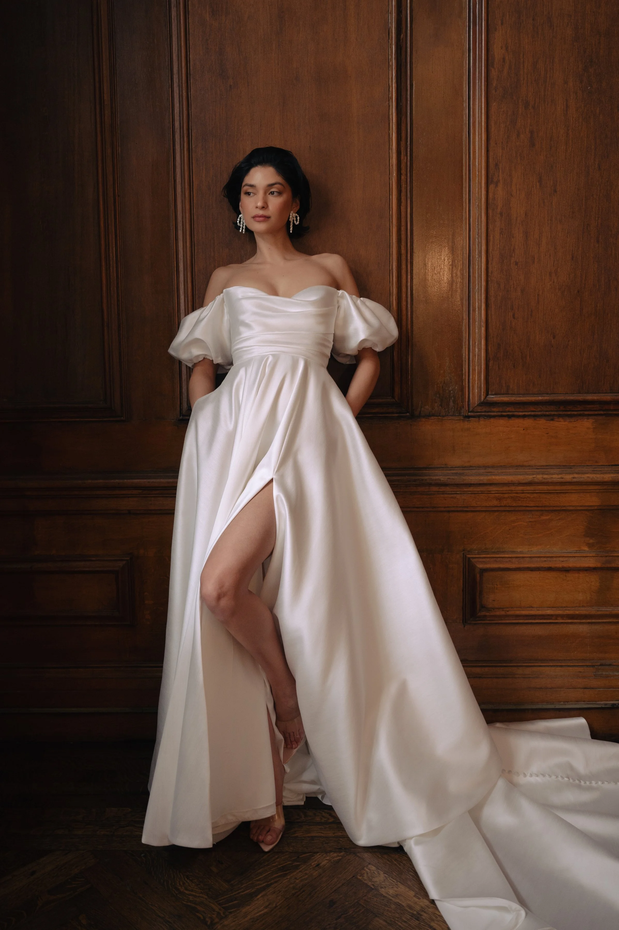 The Jenny Yoo Marisol gown is a romantic satin ball gown with a beautifully draped bodice and a sultry, sculpted cowl neckline that feels effortlessly feminine. It features a full skirt interrupted by a flattering slit and comes with detachable puff 