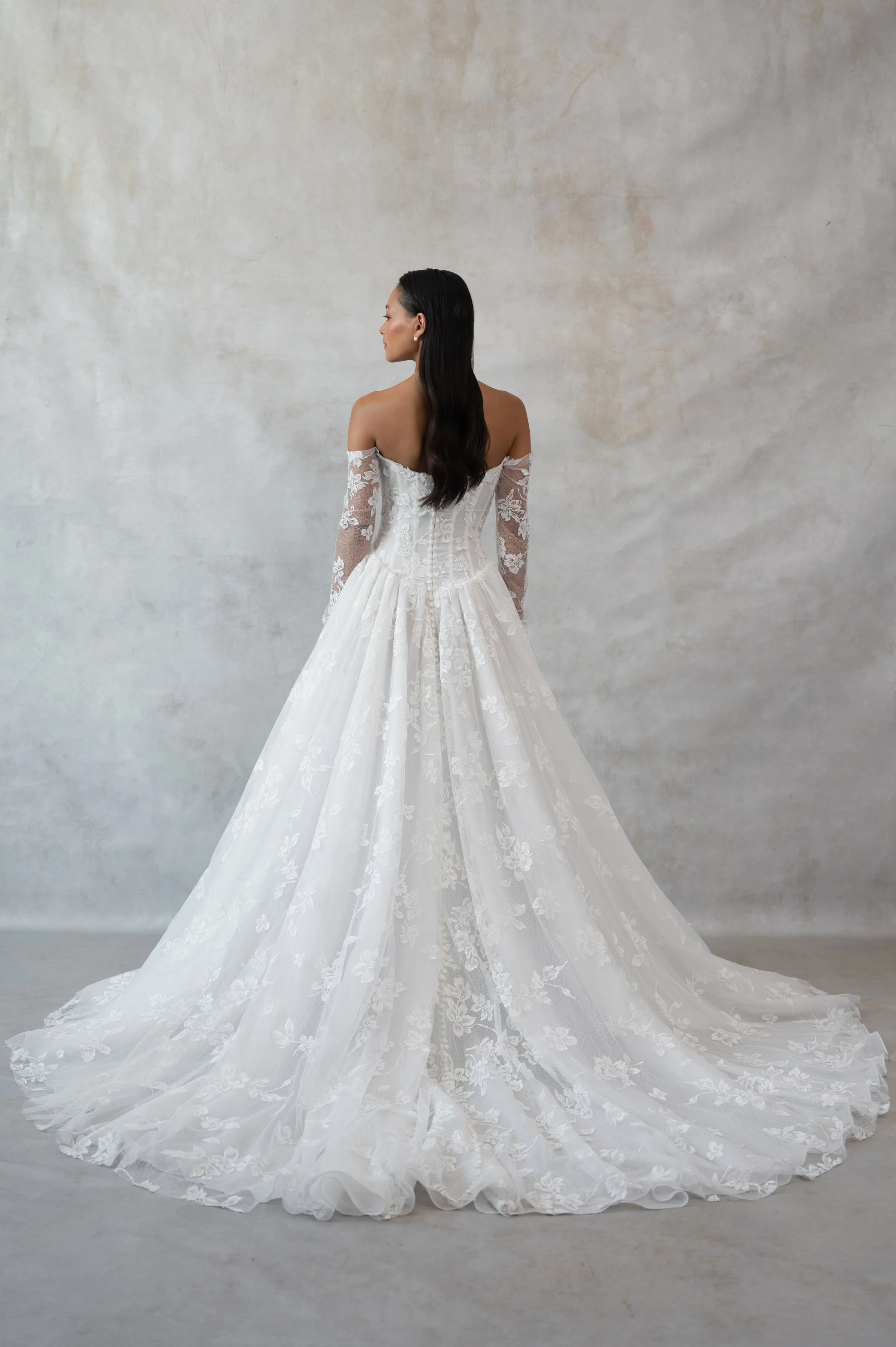 The Jenny Yoo Phoebe gown, cut in our delicately textured Isadora floral embroidery, is as modern as she is romantic. The structured Basque corset bodice leads way to a flowing gathered skirt. Detachable long sleeves lend exciting versatility.