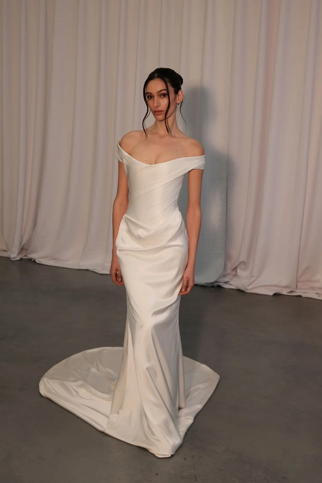 Irreverent glamour takes the spotlight in KYHA Bride Nia. Cut from sleek double satin, Nia features a highly structured bodice with a tight drape and a fit-and-flare skirt cut to accentuate the silhouette. The draping graciously falls into a floor-sw