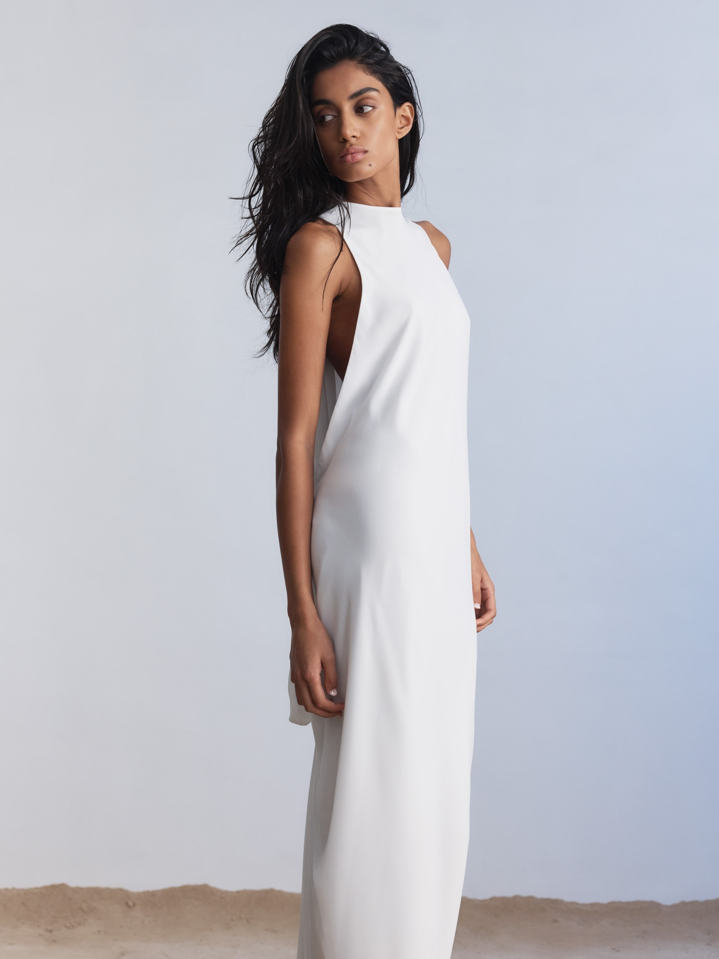 Floating on Air(eys). Rethinking the code of tradition, Aireys is defined by movement thanks to its open draped back that falls away from the body, gathering in a dramatic knot and extending into a train that descends from the knot into a soft puddle