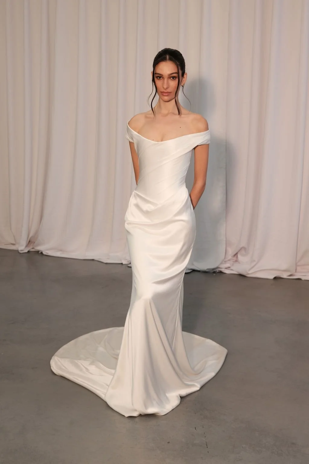 Irreverent glamour takes the spotlight in KYHA Bride Nia. Cut from sleek double satin, Nia features a highly structured bodice with a tight drape and a fit-and-flare skirt cut to accentuate the silhouette. The draping graciously falls into a floor-sw