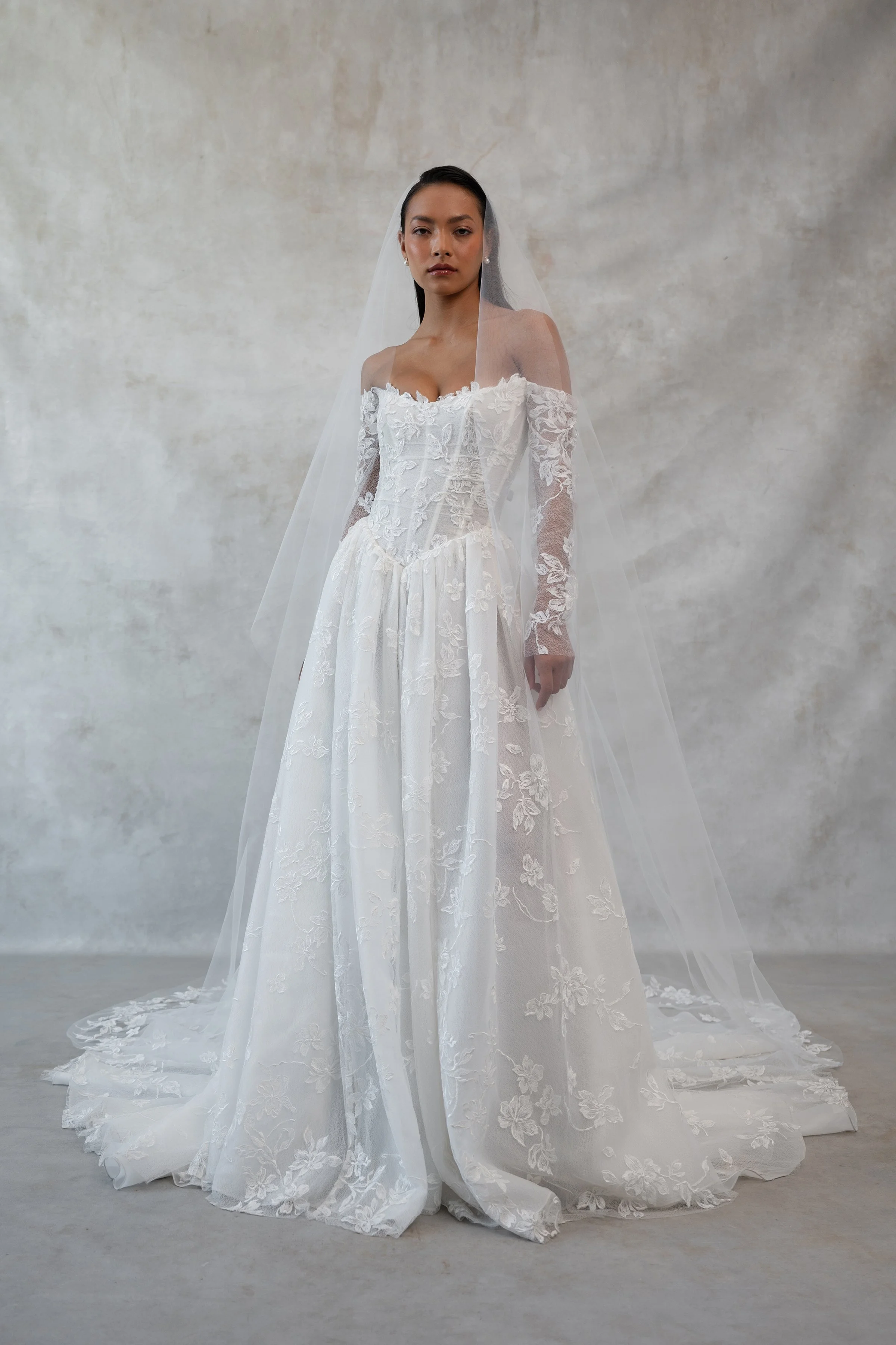 The Jenny Yoo Phoebe gown, cut in our delicately textured Isadora floral embroidery, is as modern as she is romantic. The structured Basque corset bodice leads way to a flowing gathered skirt. Detachable long sleeves lend exciting versatility.