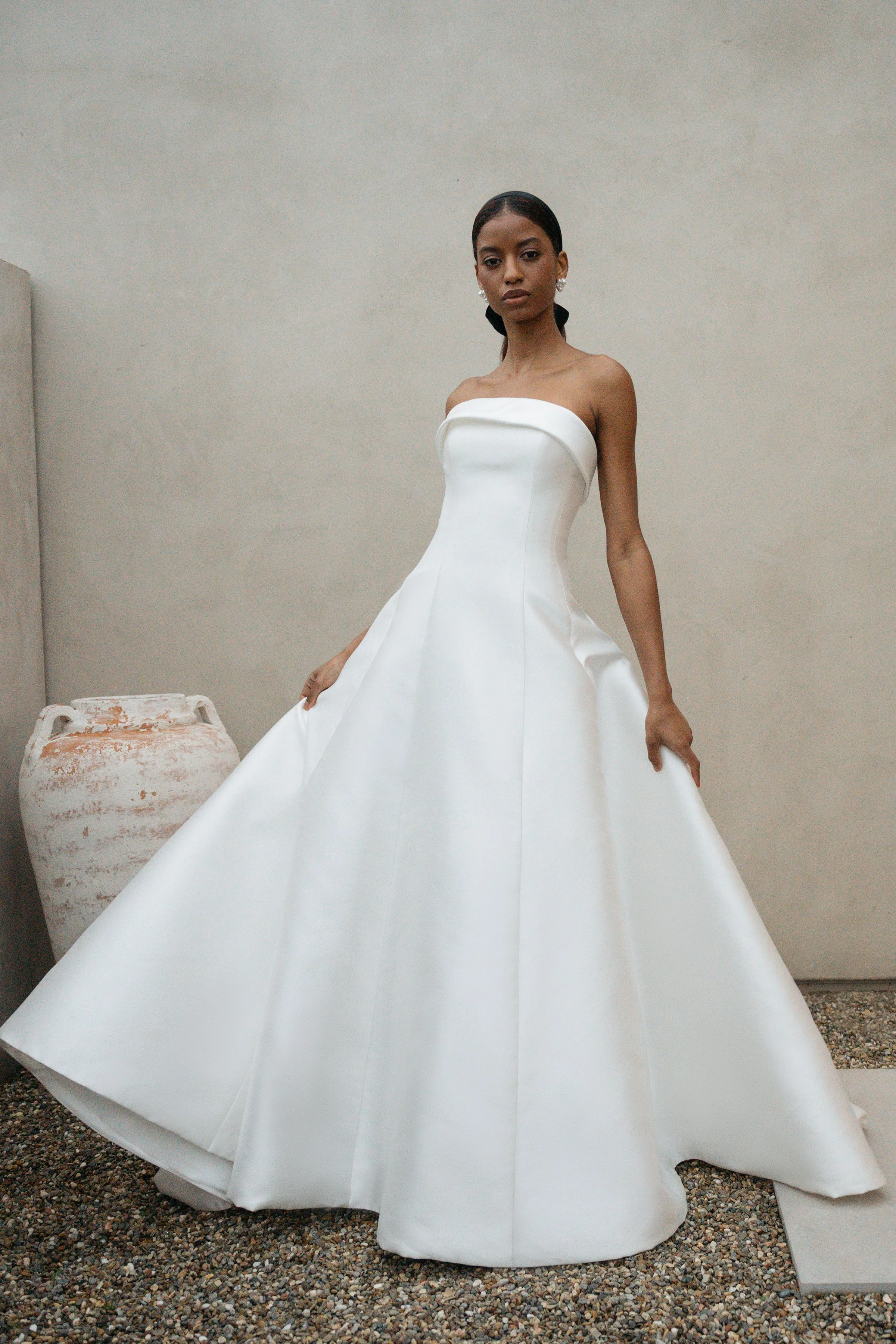 The Jenny Yoo Bridal Leah gown is a chic, timeless design in sleek Mikado that proves less is more, featuring a straight strapless neckline with subtle band detail and flattering princess seams. Its clean A-line silhouette with covered buttons down t