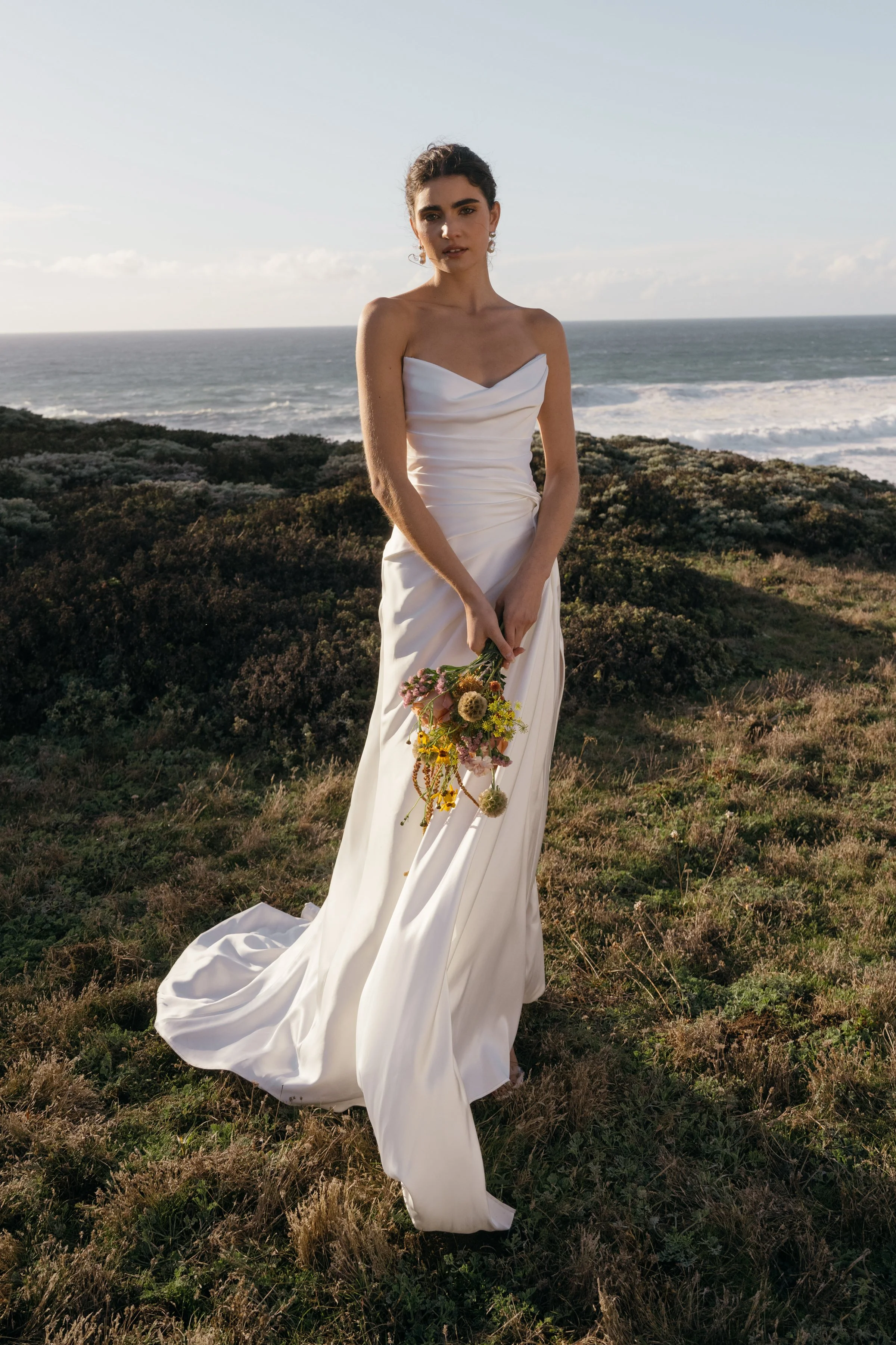 The Jenny Yoo Lana gown is a refined satin wedding dress cut in luminous Barcelona satin with elegant pleating and draping that flatters the figure, and it stands out for its versatile styling with removable long sleeves and optional sash sleeves tha