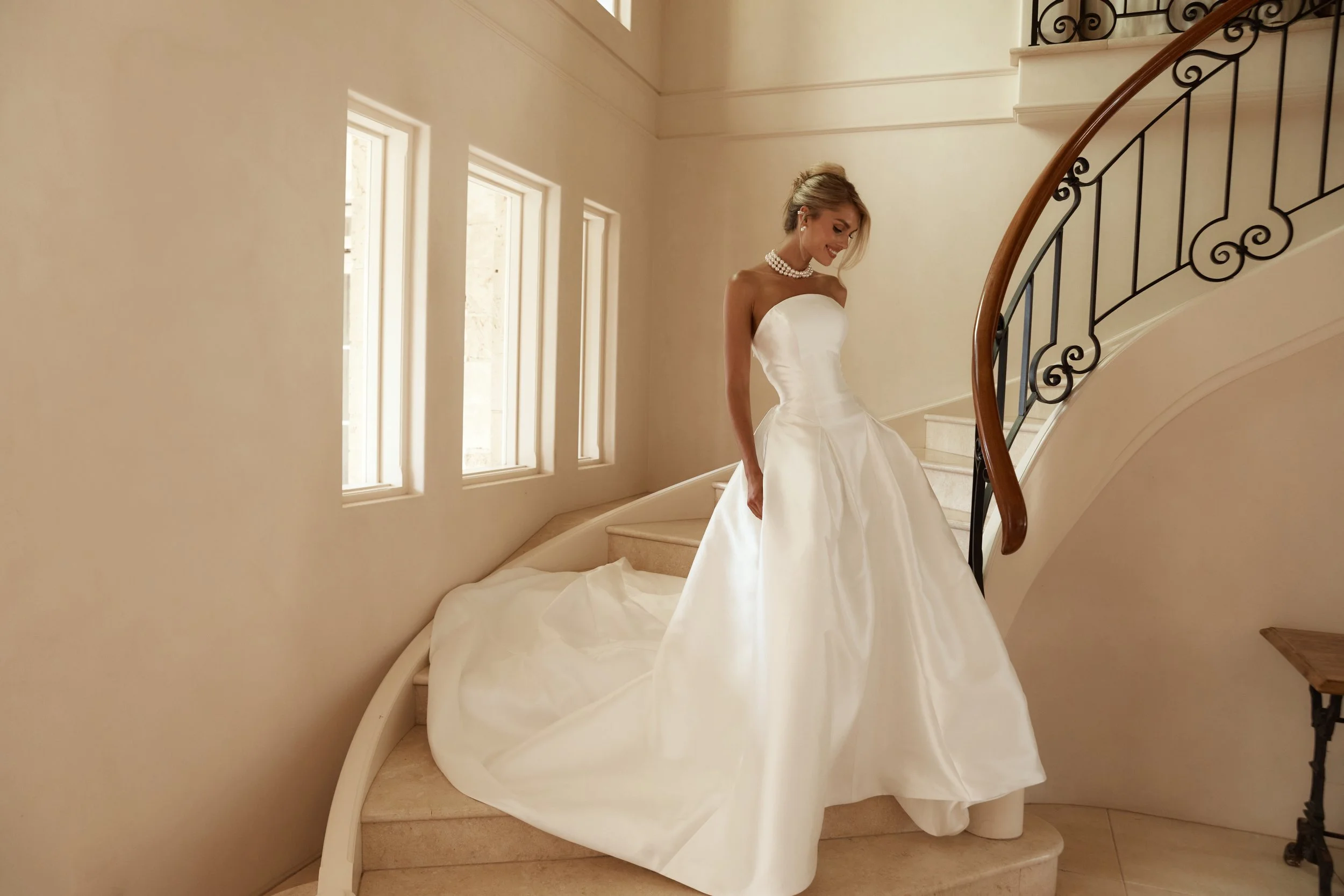 Jane Hill Bridal Dolce redefines regal with a sculptural rounded neckline and a seamless, panelled bodice that melts into the skirt. designed to elongate the figure, this minimalist silhouette features a hidden back zip for a clean finish.