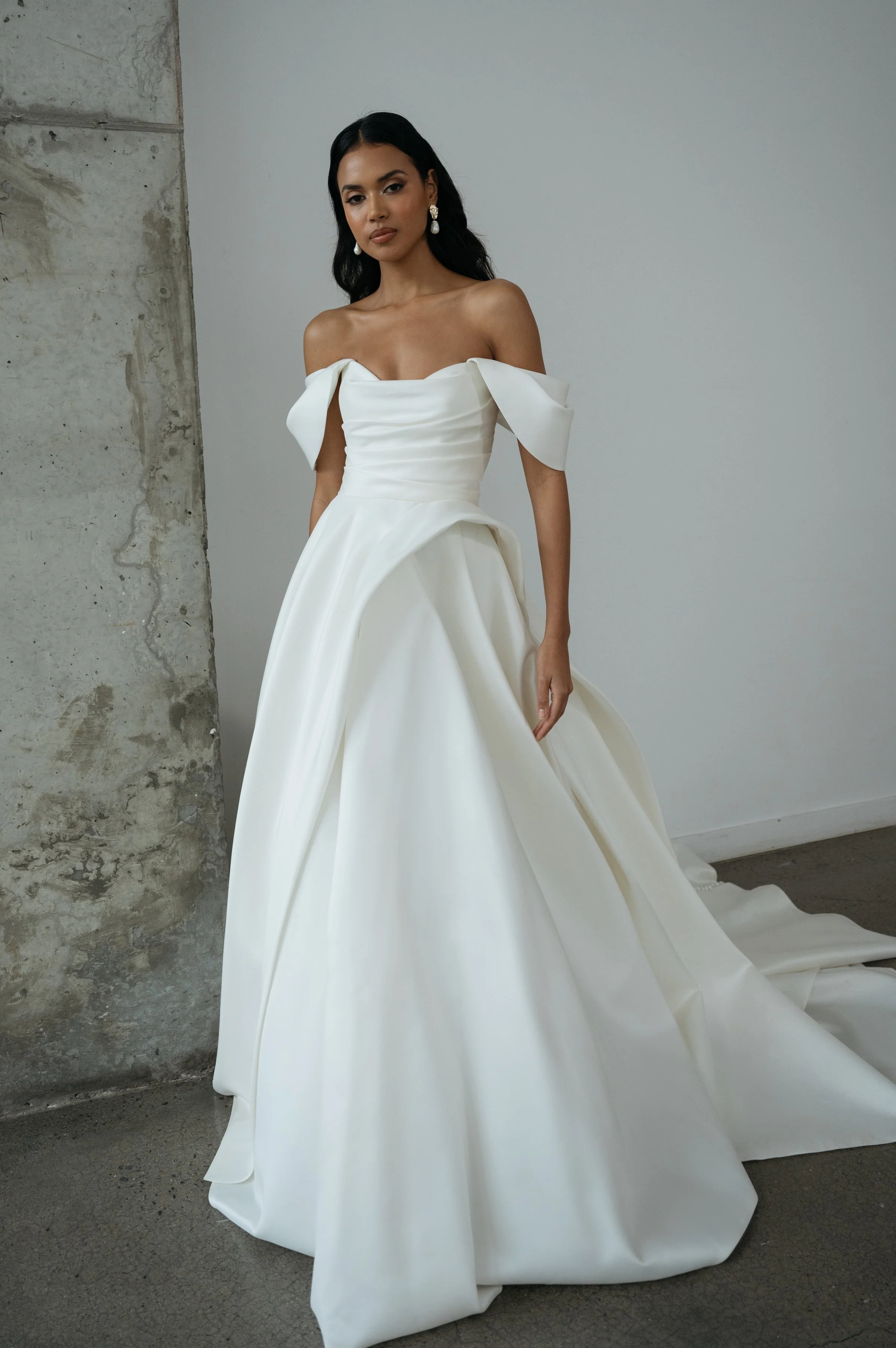 The Jenny Yoo Bridal Gardenia gown  is a refined, minimalist satin design with a clean, structured bodice and effortless drape. It features a flattering neckline and a sleek, flowing skirt that creates a modern yet timeless bridal silhouette.