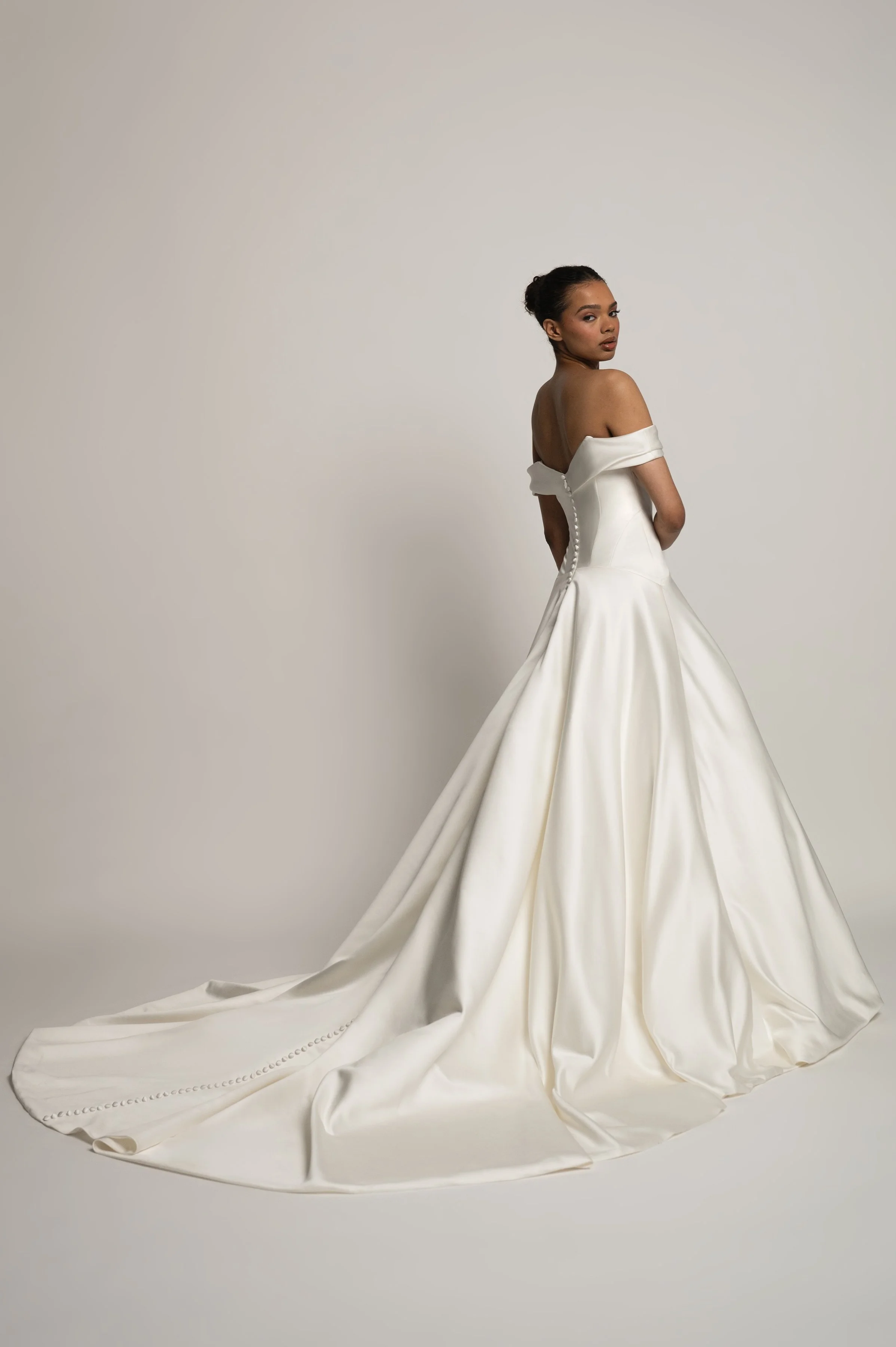 The Jenny Yoo Bridal Greer gown, our second collaboration with renowned bridal stylist, Hope LaVine, is as modern as she is timeless. Featuring a softly draped off the shoulder neckline, angled corset seam details, and a curved drop waist, she is stu