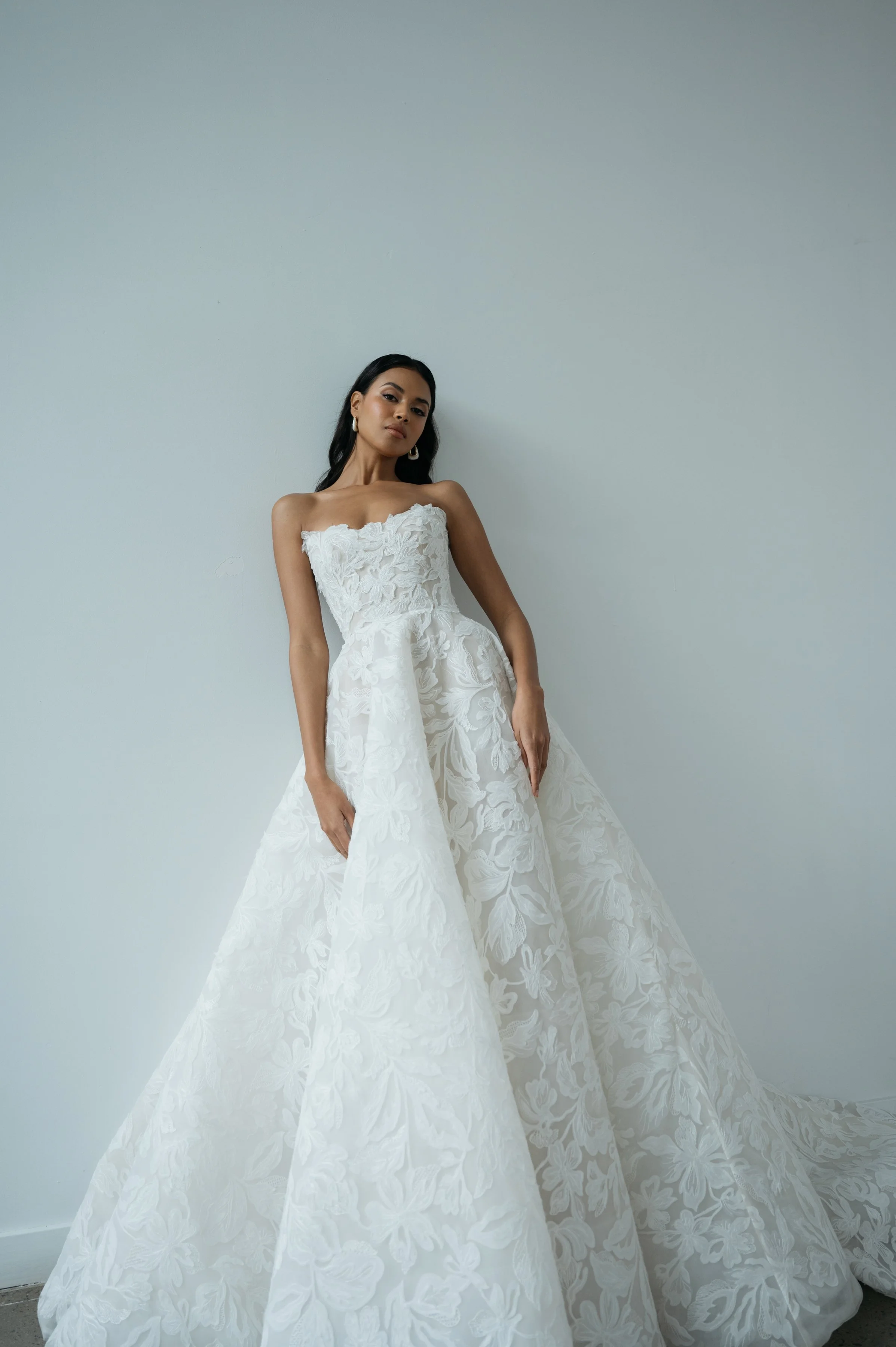 The Jenny Yoo Ezra gown is an ethereal ball gown that feels as though it floats on air, crafted in intricate Iris cutwork tulle over a dramatic crinoline skirt that’s diaphanous and light. It features a fully corseted, flattering bodice and comes wit