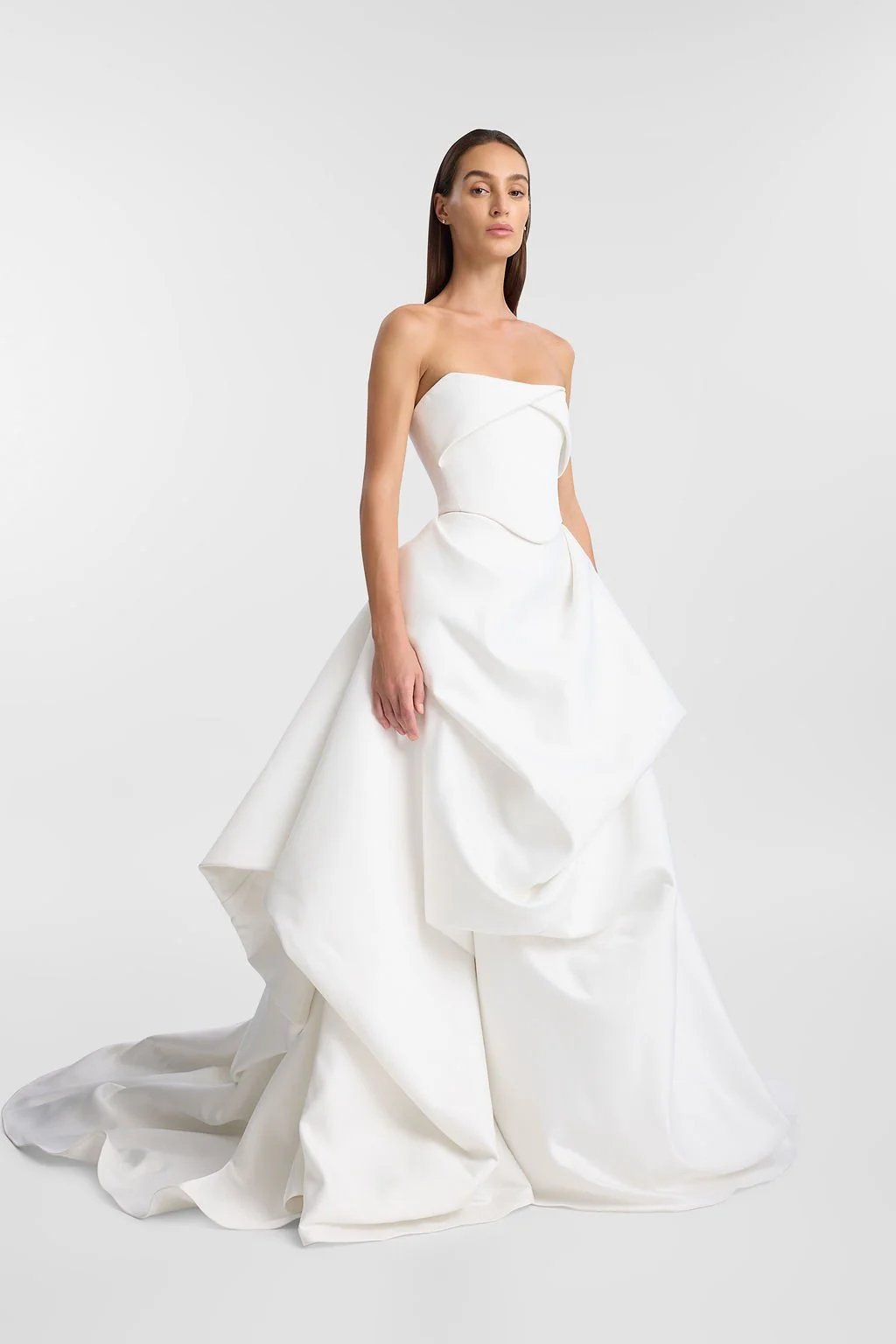 On cloud nine in KYHA Bride Lowe. Designed from lustrous duchess satin, Lowe’s bold focus on shape and head-turning structural draping creates soft, cloud-like moments. Featuring a sculpted waistband and a floor-grazing full skirt with internal netti