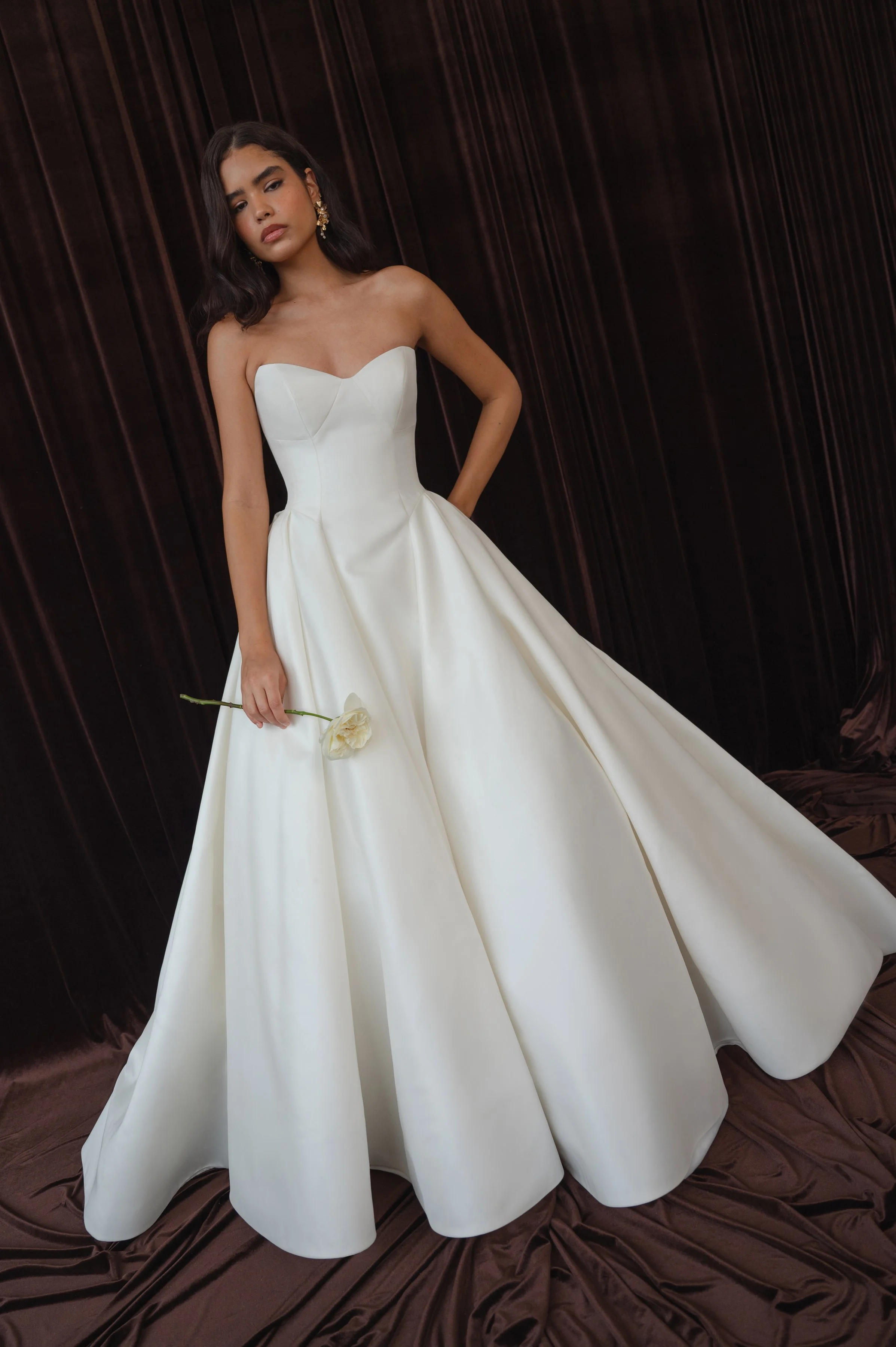 The Jenny Yoo Bridal Colette gown, cut in our light and lustrous Italian taffeta fabric is a clean, yet striking show stopper. Intricate seam details sculpt a bustier bodice and subtle drop waist silhouette. Pleats in the ball skirt create dramatic v
