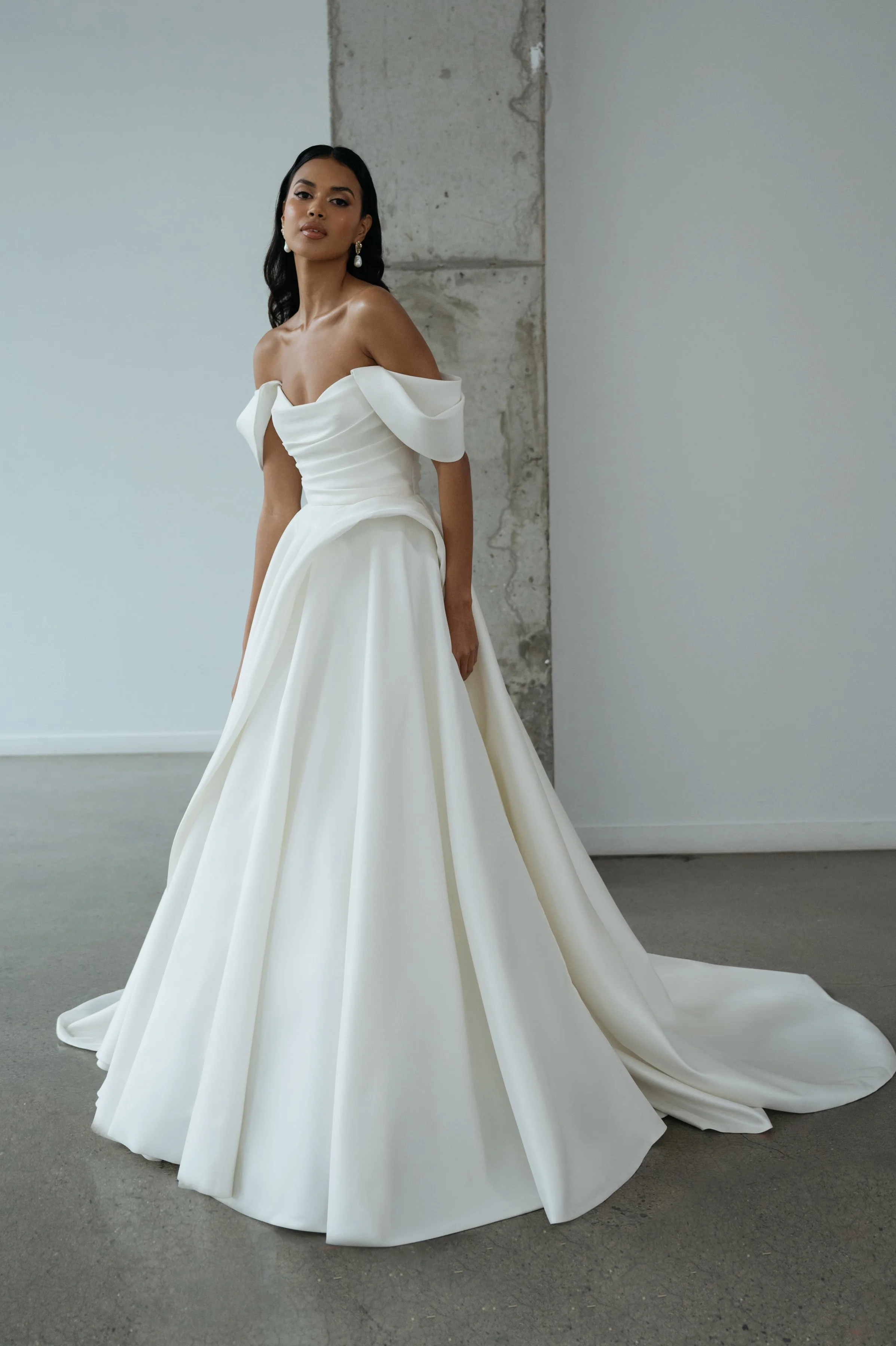 The Jenny Yoo Bridal Gardenia gown  is a refined, minimalist satin design with a clean, structured bodice and effortless drape. It features a flattering neckline and a sleek, flowing skirt that creates a modern yet timeless bridal silhouette.