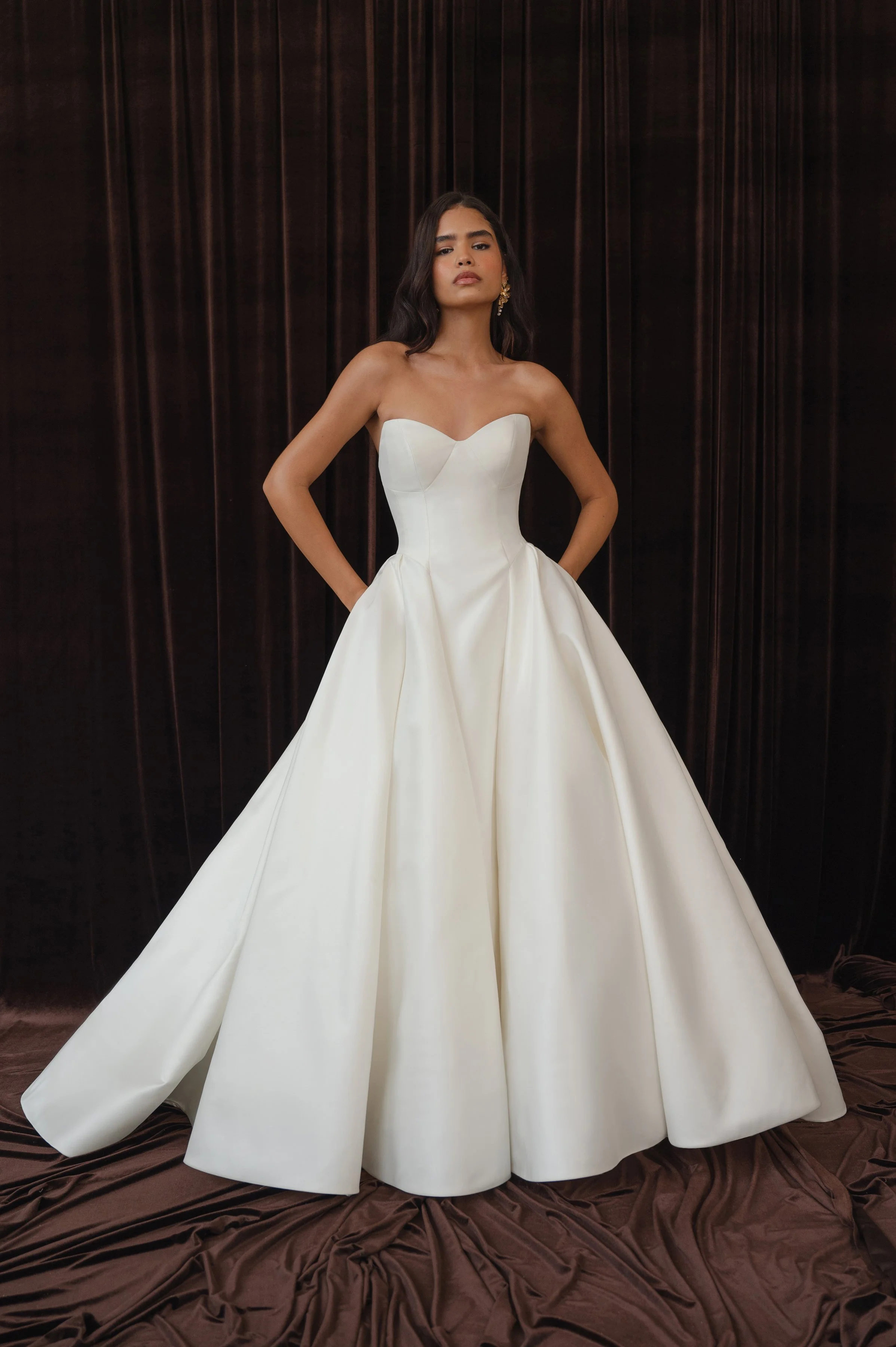 The Jenny Yoo Bridal Colette gown, cut in our light and lustrous Italian taffeta fabric is a clean, yet striking show stopper. Intricate seam details sculpt a bustier bodice and subtle drop waist silhouette. Pleats in the ball skirt create dramatic v