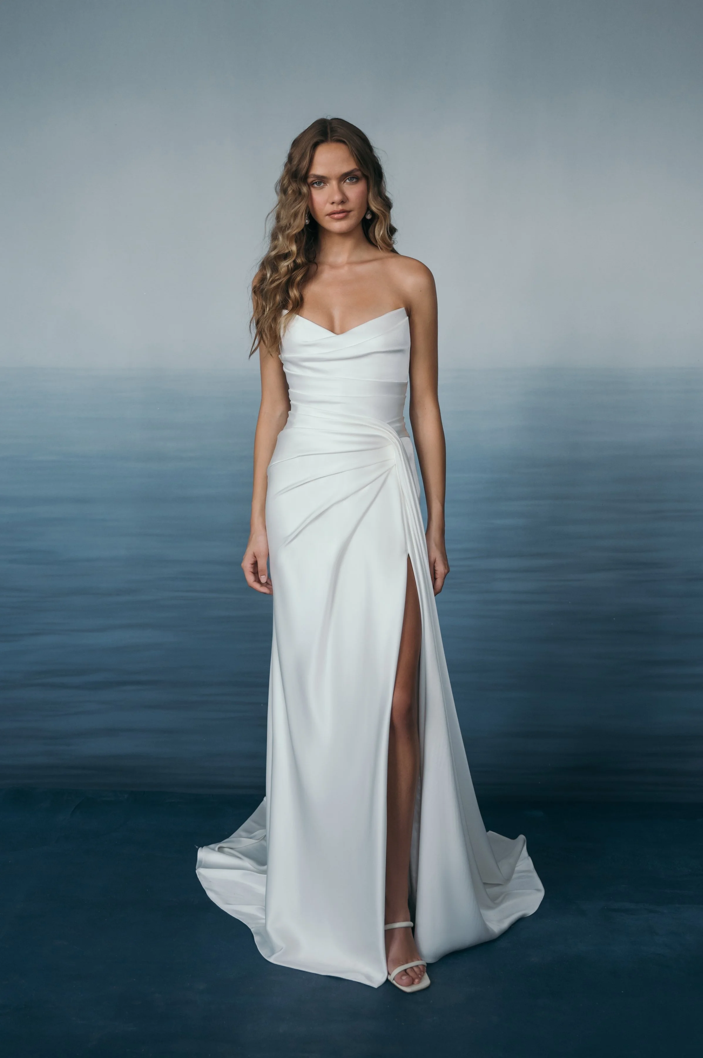 The Jenny Yoo Lana gown is a refined satin wedding dress cut in luminous Barcelona satin with elegant pleating and draping that flatters the figure, and it stands out for its versatile styling with removable long sleeves and optional sash sleeves tha