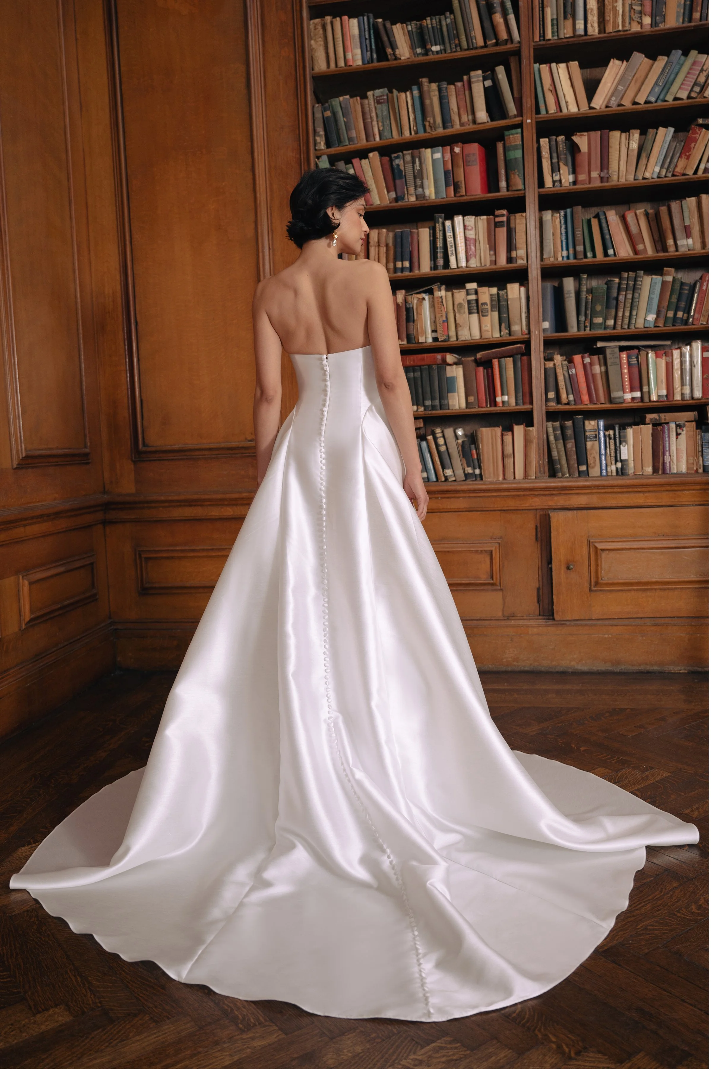The Jenny Yoo Romina gown is a refined strapless A-line wedding dress crafted from lightweight, luminous canopy taffeta with a beautifully draped cowl bodice and sculpted drop-waist silhouette that feels both modern and timeless. Its soft, elegant li