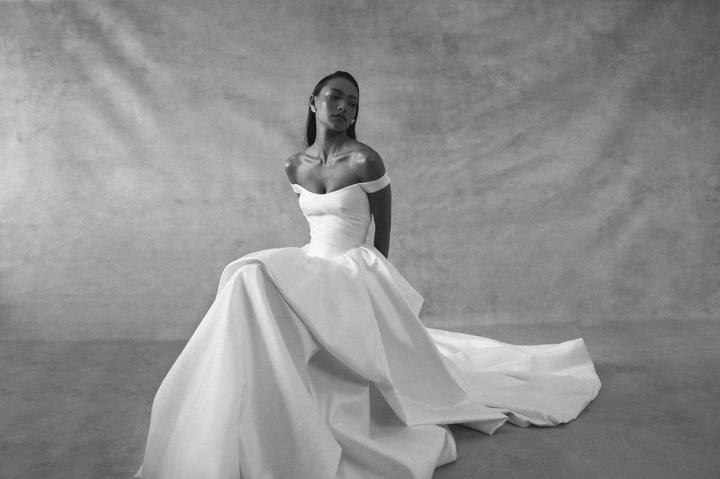 The Jenny Yoo Bridal Elle gown, cut in our lofty Italian taffeta, is a true chameleon. Featuring a corseted bodice with a flattering Basque waist and a delicate off the shoulder strap, her voluminous skirt transforms into a dramatic high-low look per