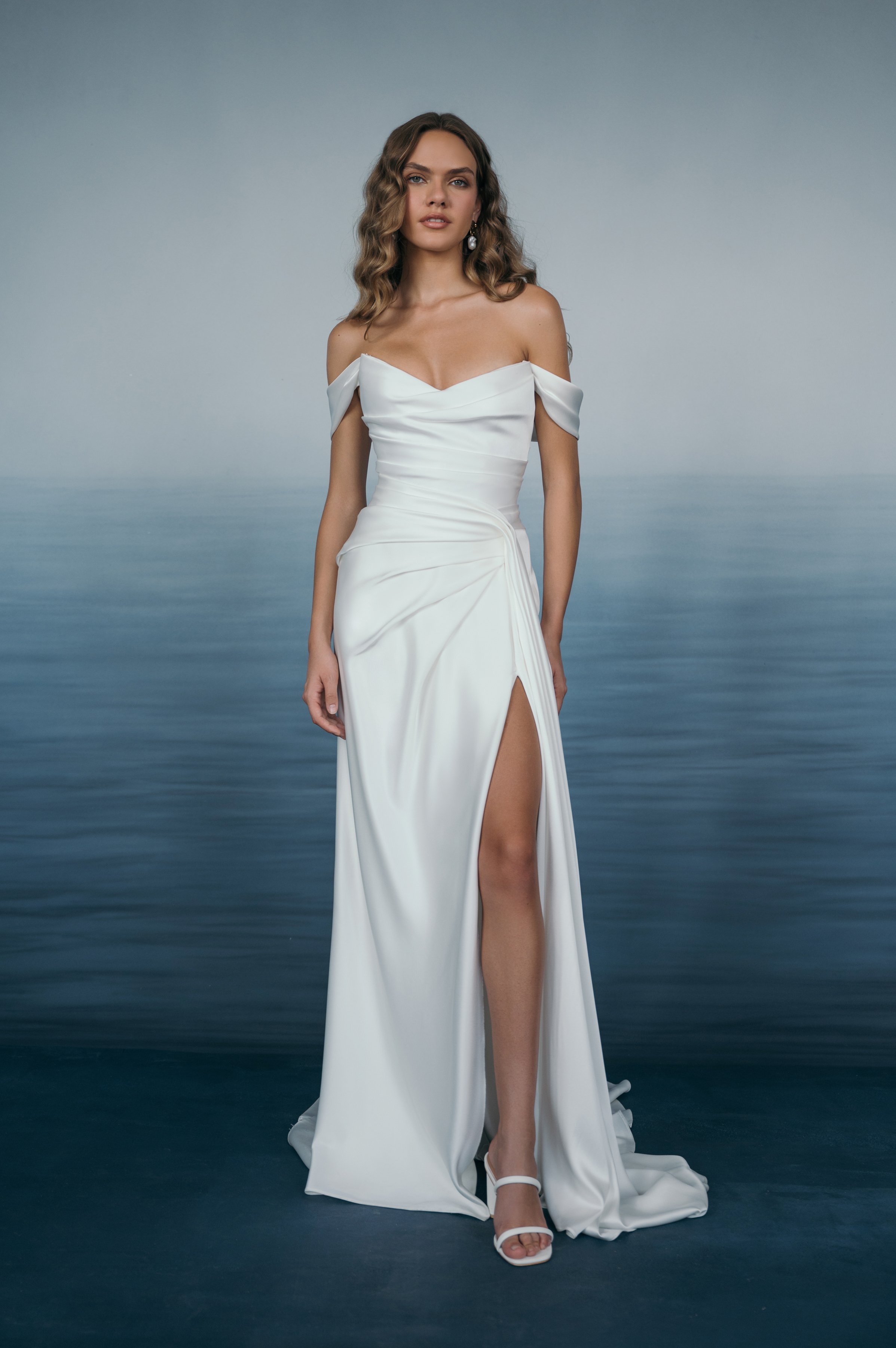 The Jenny Yoo Lana gown is a refined satin wedding dress cut in luminous Barcelona satin with elegant pleating and draping that flatters the figure, and it stands out for its versatile styling with removable long sleeves and optional sash sleeves tha