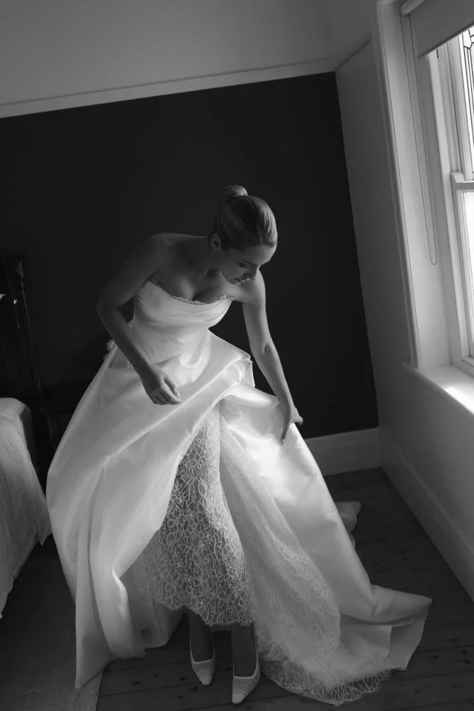 The Mariana Hardwick Maxine Wedding Dress is effortlessly modern with a timeless edge. Designed for the cool, confident bride, this gown delivers a clean, sculpted silhouette with refined detailing that feels understated yet elevated. Crafted from lu