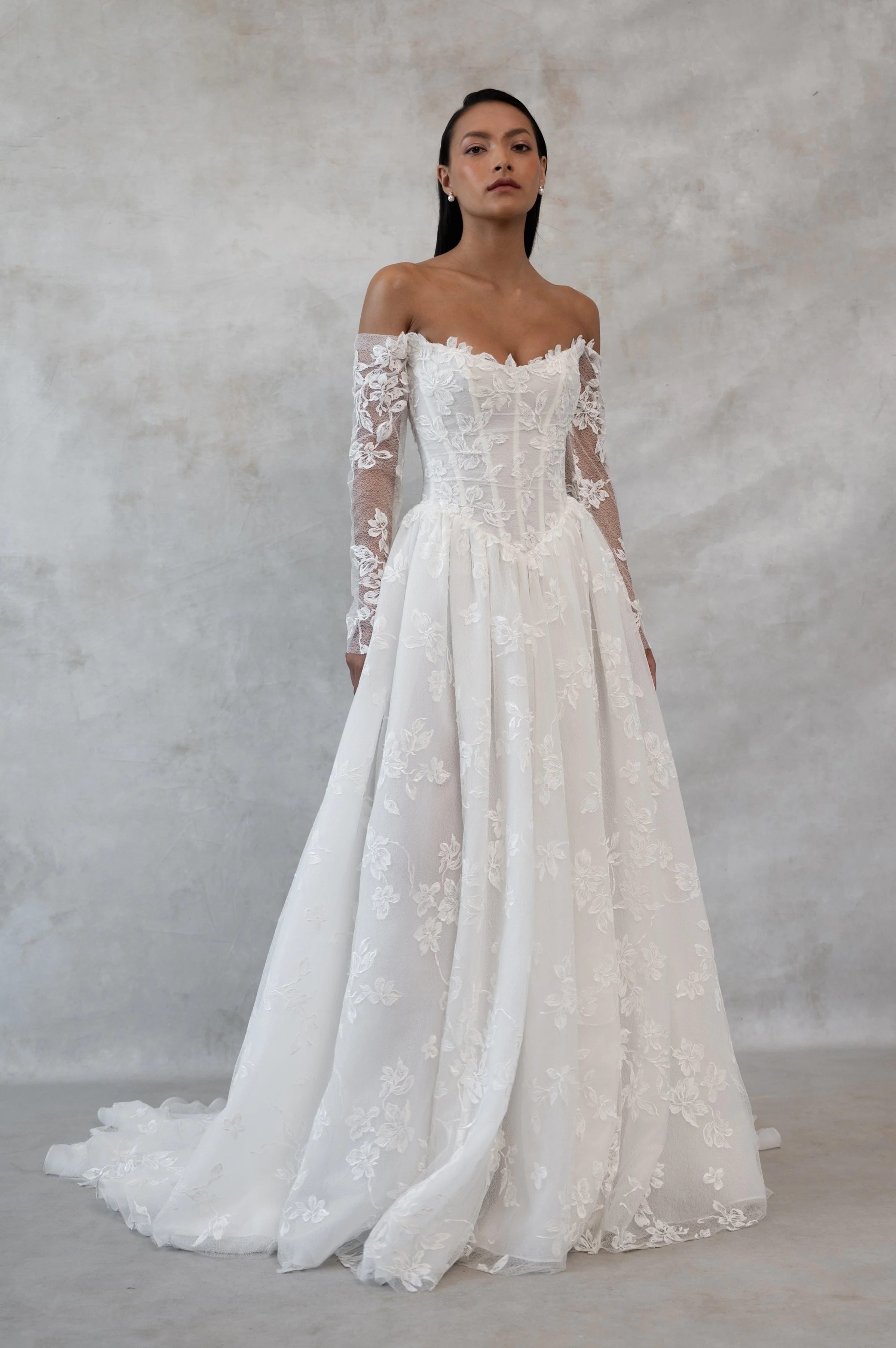 The Jenny Yoo Phoebe gown, cut in our delicately textured Isadora floral embroidery, is as modern as she is romantic. The structured Basque corset bodice leads way to a flowing gathered skirt. Detachable long sleeves lend exciting versatility.