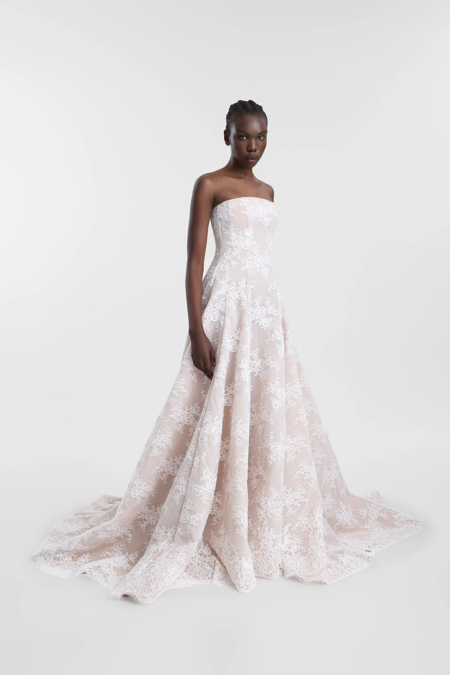Laced with ethereal romance in KYHA Bride Dalias. A modern take with old-world energy, Dalias is crafted from intricate corded white lace with a chiffon underlay and a scalloped lace trim at the hem. The strapless structured bodice and full skirt and