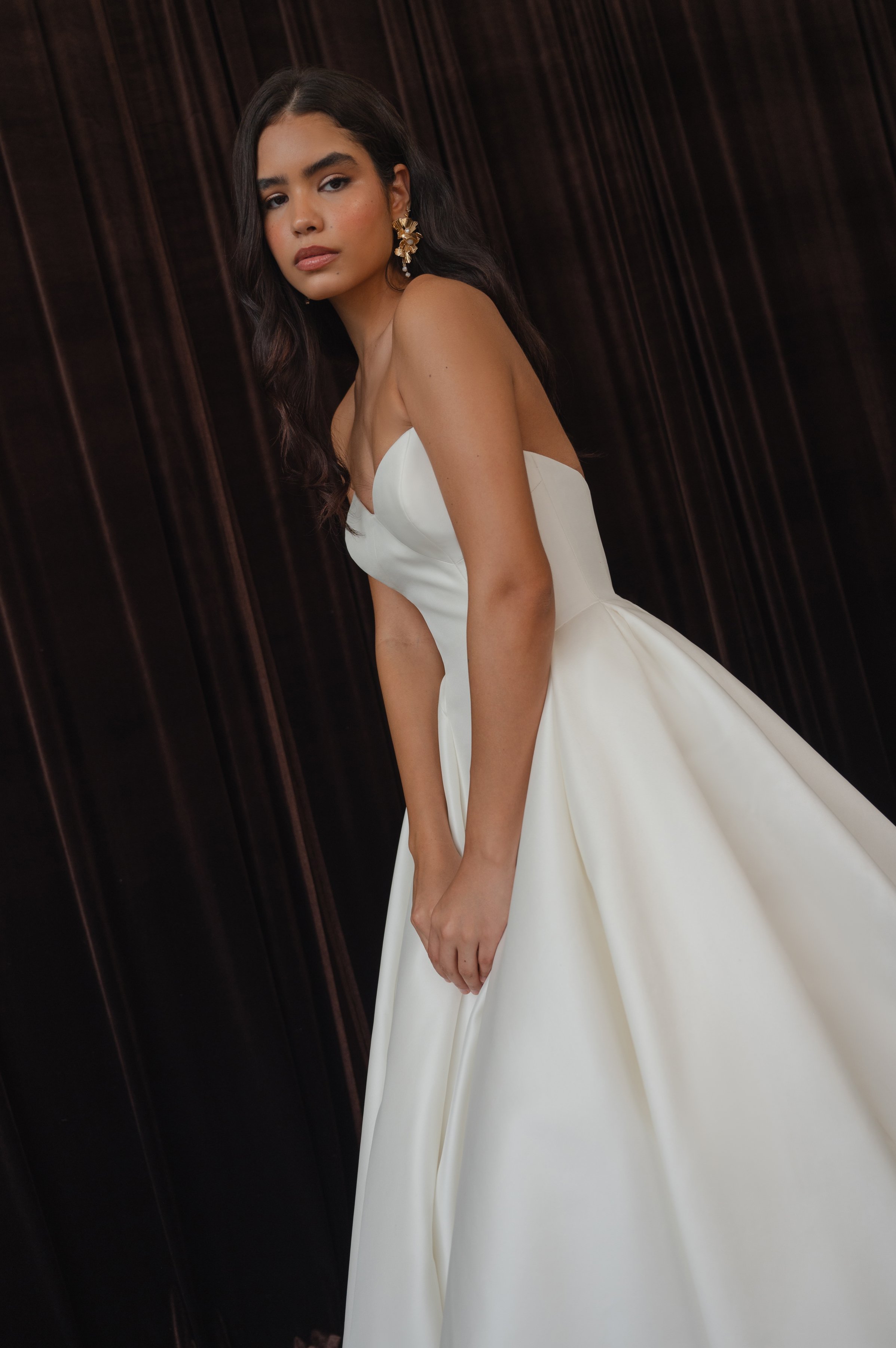 The Jenny Yoo Bridal Colette gown, cut in our light and lustrous Italian taffeta fabric is a clean, yet striking show stopper. Intricate seam details sculpt a bustier bodice and subtle drop waist silhouette. Pleats in the ball skirt create dramatic v