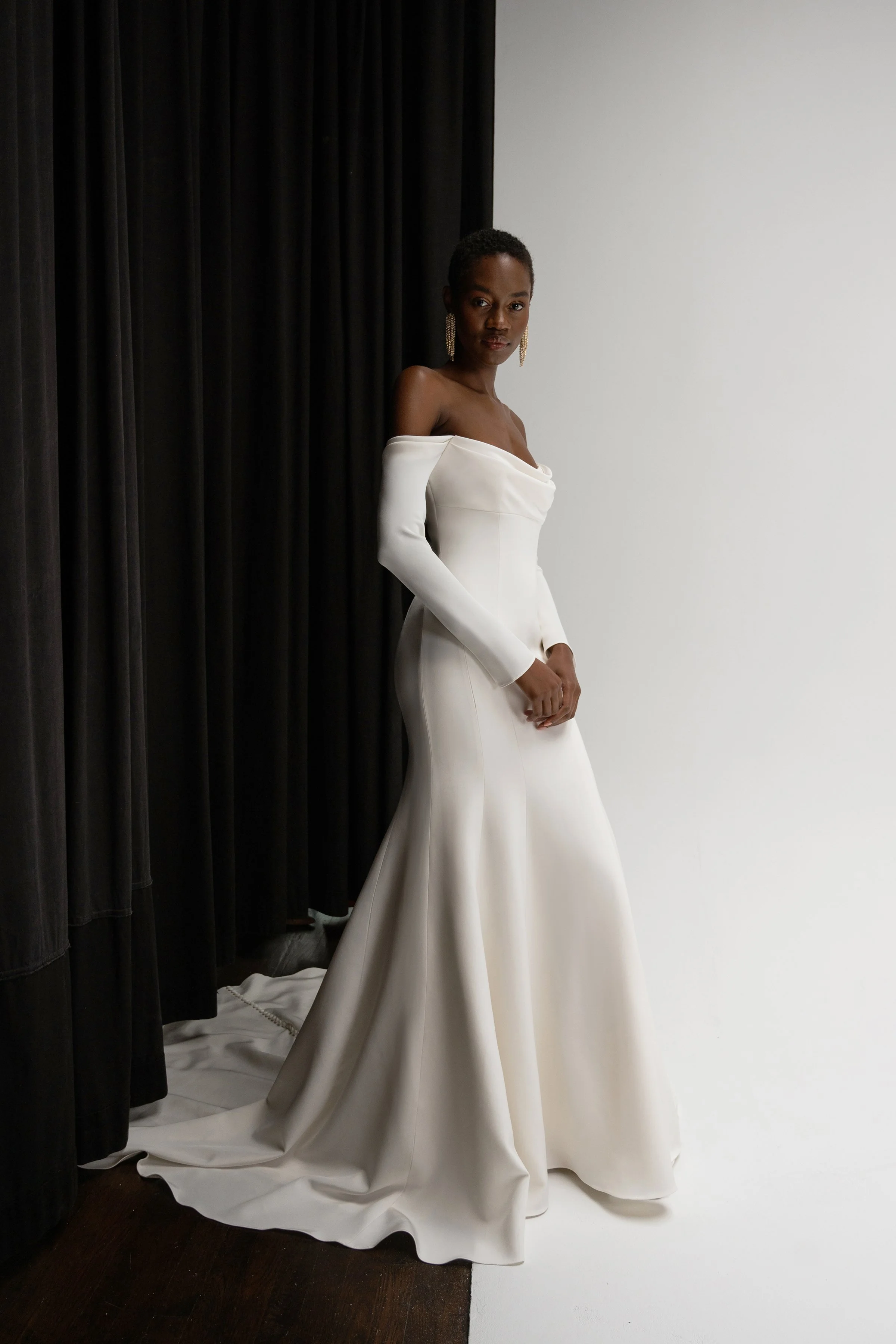 The Jenny Yoo Briar gown is a sophisticated fit-and-flare bridal dress in lustrous silk crepe with a softly draped empire bodice that flatters the décolletage and highlights the shoulders. It features long, slim sleeves and an off-the-shoulder or ele