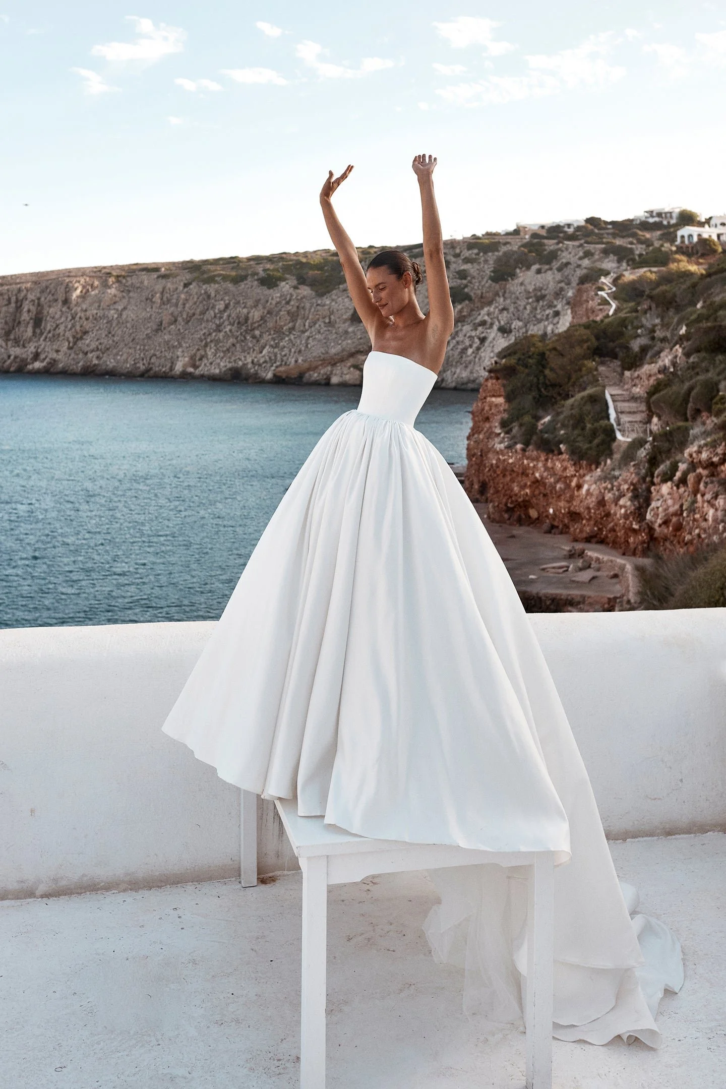 Clean lines, dramatic proportions and more than a touch of je ne sais quoi define KYHA Bride Cleo. A minimalist reinvention of the traditional ballgown, Cleo's clean, strapless bodice is defined by a modern straight neckline and unexpected low-dipped