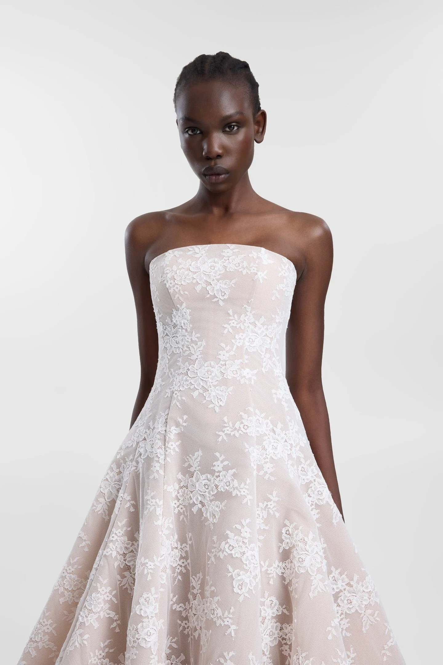 Laced with ethereal romance in KYHA Bride Dalias. A modern take with old-world energy, Dalias is crafted from intricate corded white lace with a chiffon underlay and a scalloped lace trim at the hem. The strapless structured bodice and full skirt and