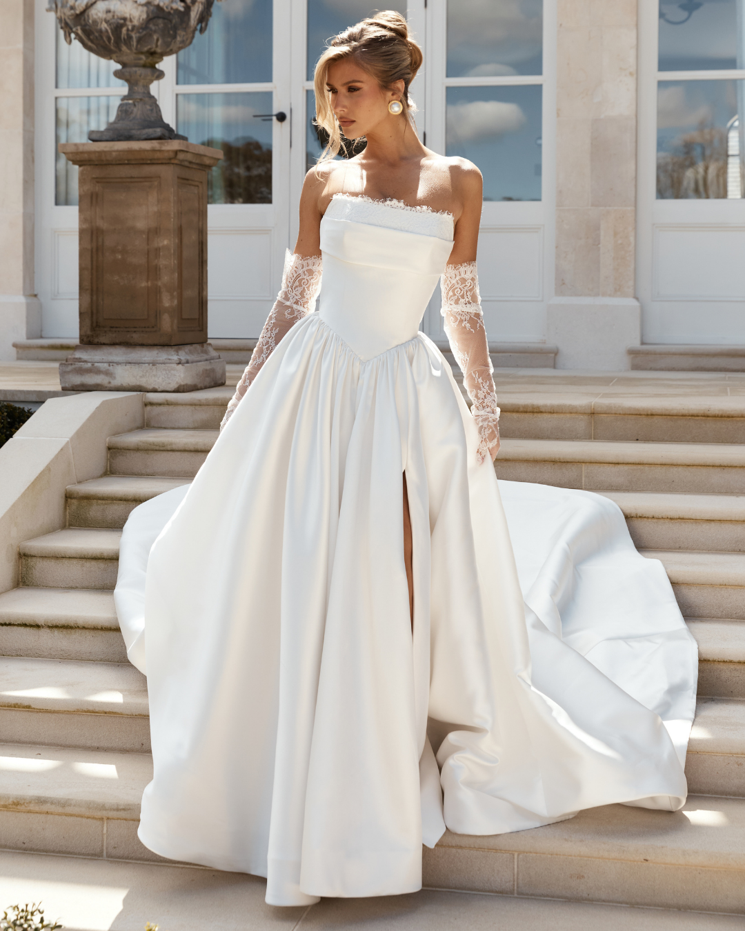 A timeless statement with a touch of couture romance, Jane Hill Bridal Audrey pairs a beautifully structured bodice with delicate lace trim that softens the strapless neckline. The full mikado skirt is truly one-of-a-kind—voluminous yet refined—with 