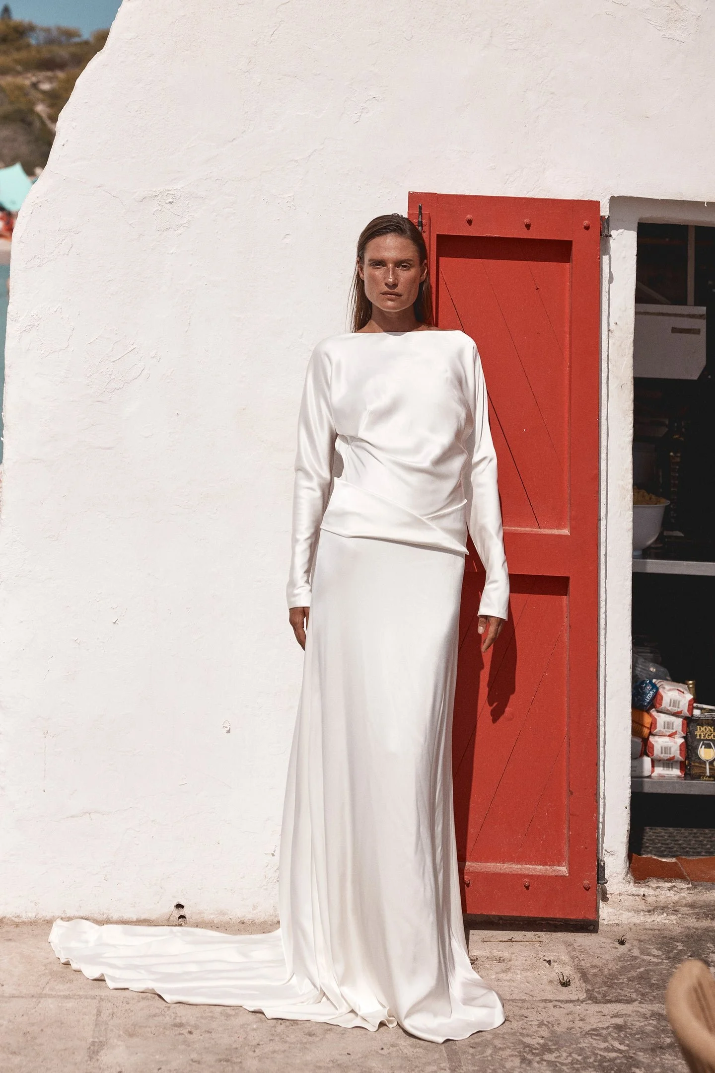 Meet KYHA Bride Lola, spirit of the 70s that will live in your head rent-free. Cut for a slightly oversized fit in luxe double satin, Lola features long batwing sleeves, a twisted sash at the hip, and a skirt with a soft train. The open back adds an 