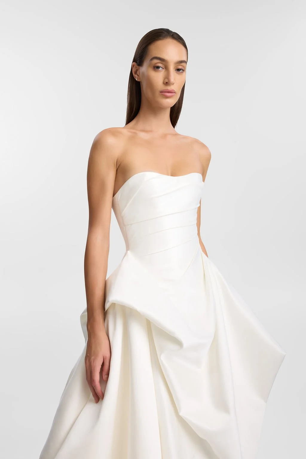 KYHA Bride Preston: an ode to eras past. A fresh take on tradition, Preston brings a modern edge thanks to its structural draping, showstopping train and architectural dropped waist. Crafted from luxe silk satin, Preston’s strapless silhouette, struc