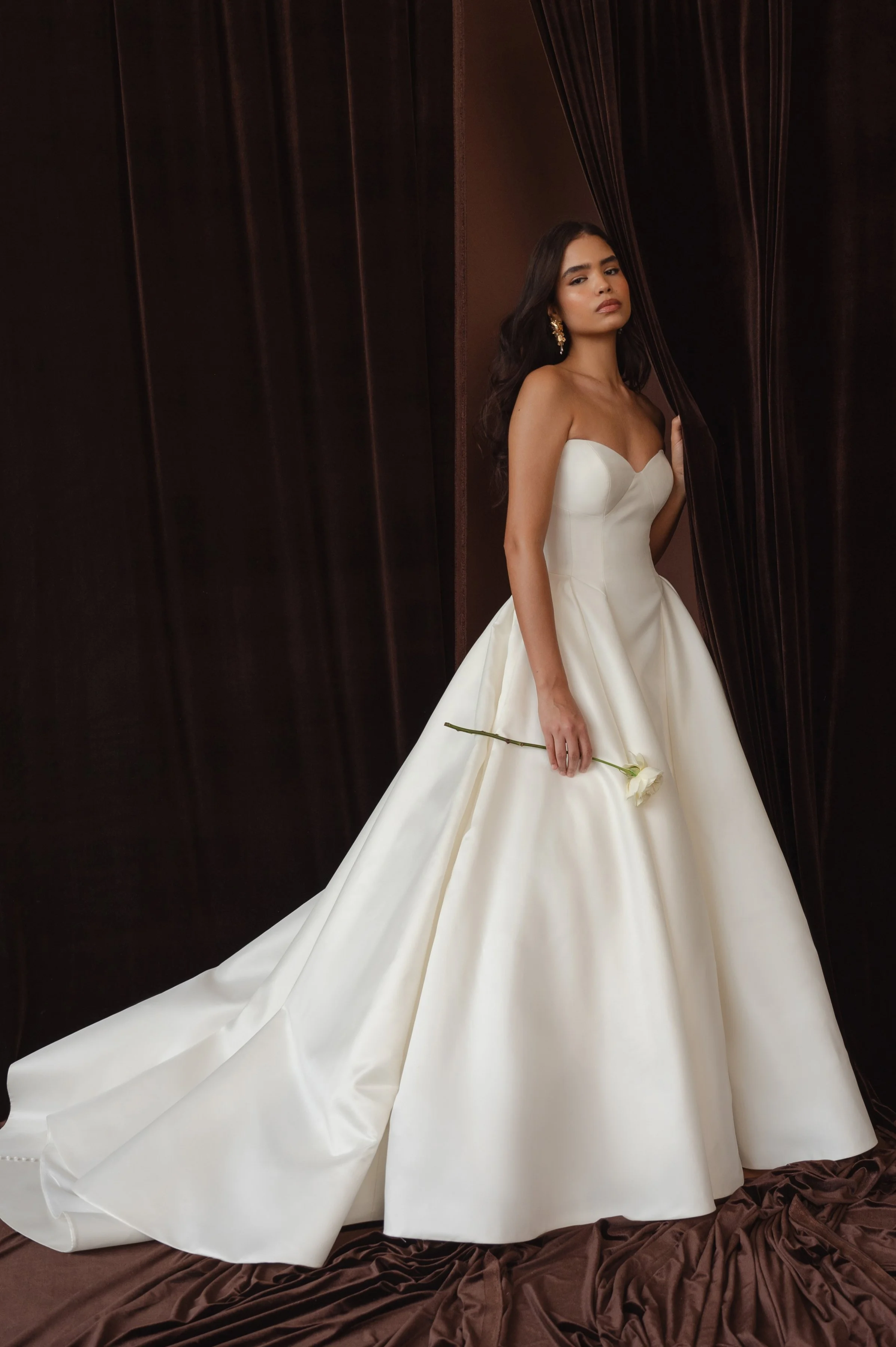 The Jenny Yoo Bridal Colette gown, cut in our light and lustrous Italian taffeta fabric is a clean, yet striking show stopper. Intricate seam details sculpt a bustier bodice and subtle drop waist silhouette. Pleats in the ball skirt create dramatic v