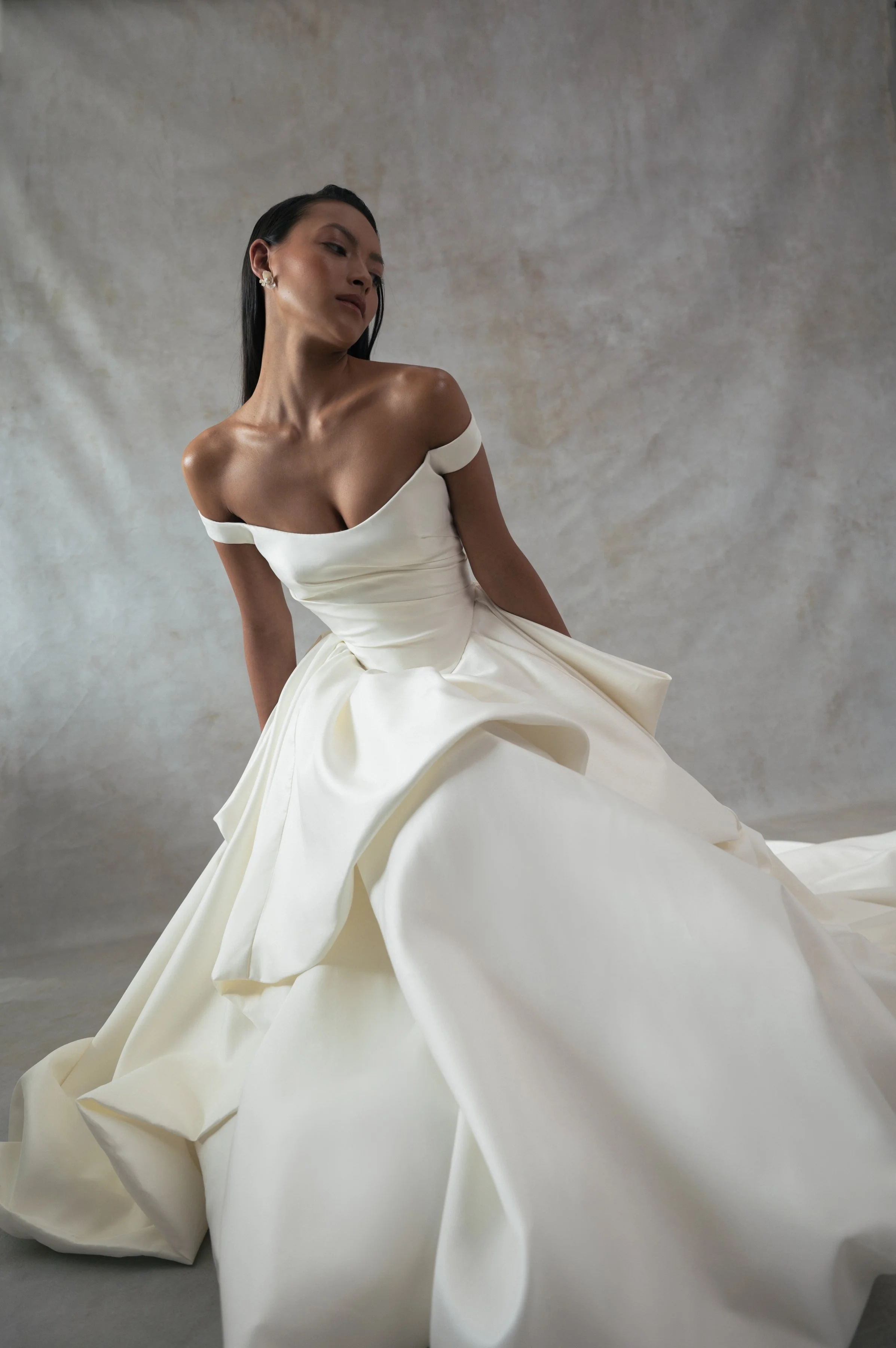 The Jenny Yoo Bridal Elle gown, cut in our lofty Italian taffeta, is a true chameleon. Featuring a corseted bodice with a flattering Basque waist and a delicate off the shoulder strap, her voluminous skirt transforms into a dramatic high-low look per