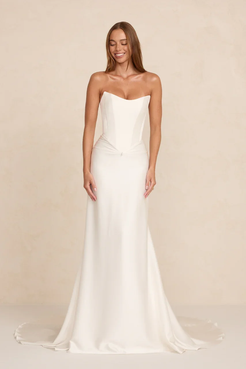 The MWL Natalie is crafted from two layers of Crepe Satin with a fluid drape and soft sheen. A cinched scooped bodice defines the waist, while a pinched front and illustrious fabric creates an exceptional bridal look. Natalie will be available at Hal