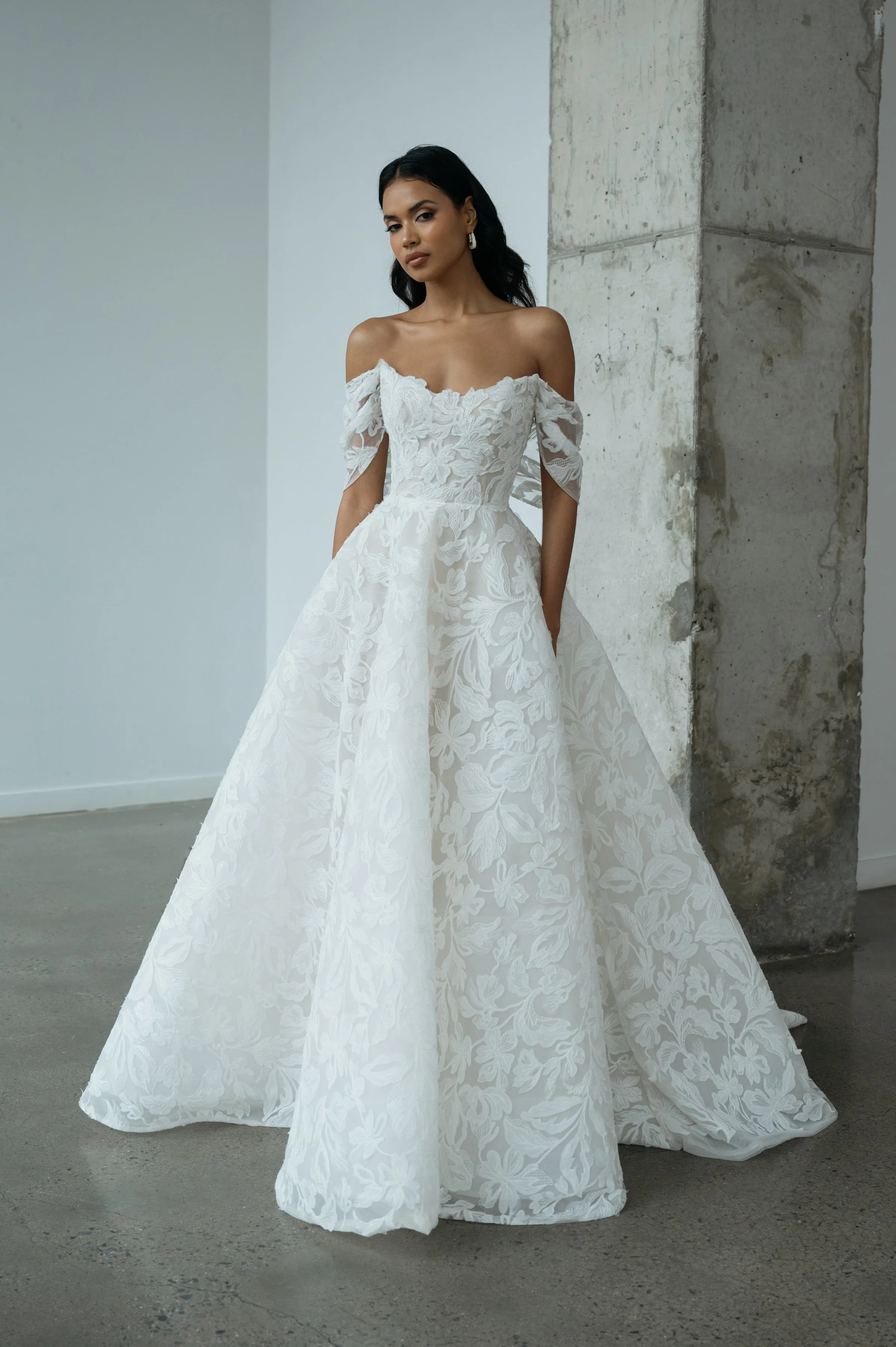 The Jenny Yoo Ezra gown is an ethereal ball gown that feels as though it floats on air, crafted in intricate Iris cutwork tulle over a dramatic crinoline skirt that’s diaphanous and light. It features a fully corseted, flattering bodice and comes wit