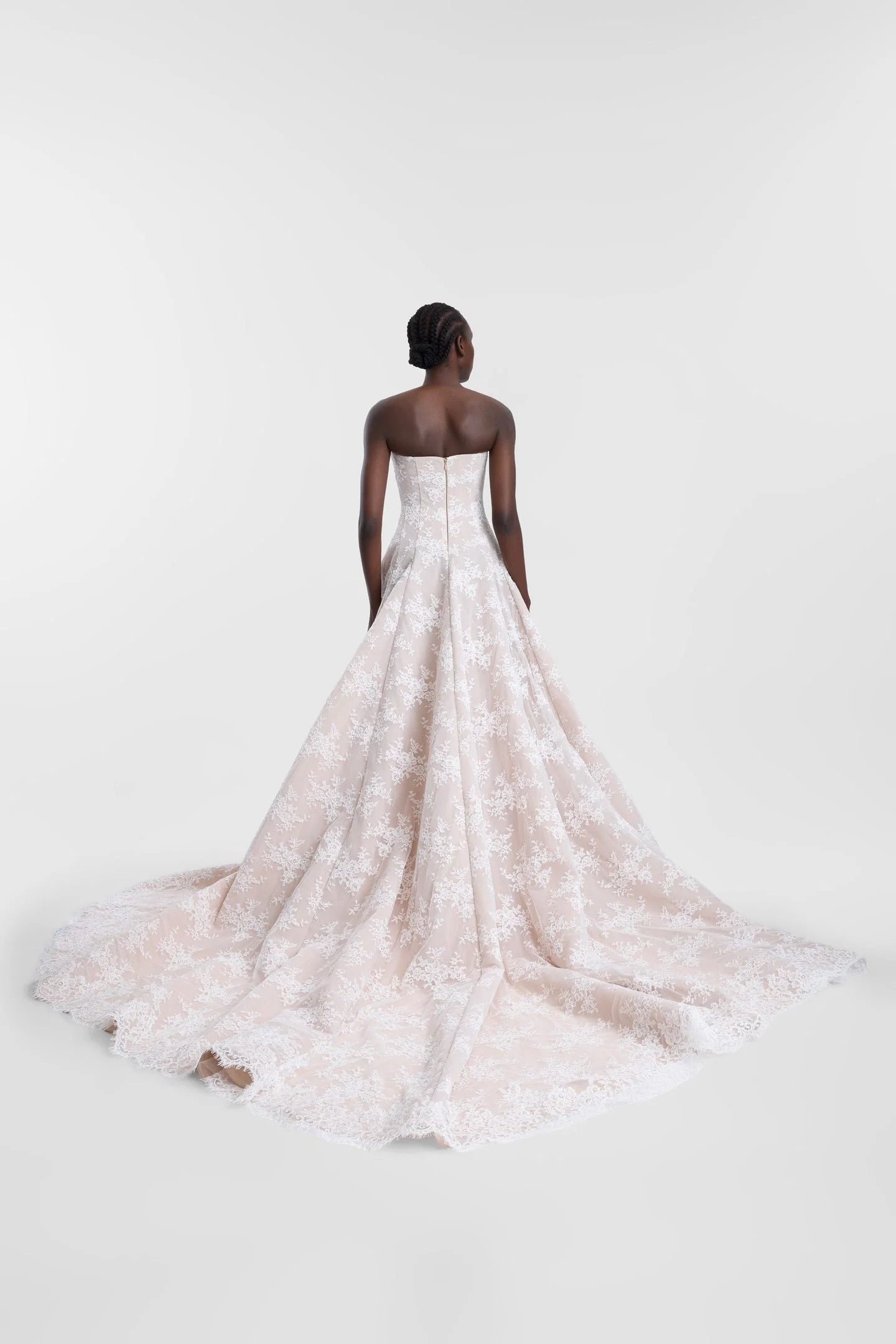 Laced with ethereal romance in KYHA Bride Dalias. A modern take with old-world energy, Dalias is crafted from intricate corded white lace with a chiffon underlay and a scalloped lace trim at the hem. The strapless structured bodice and full skirt and