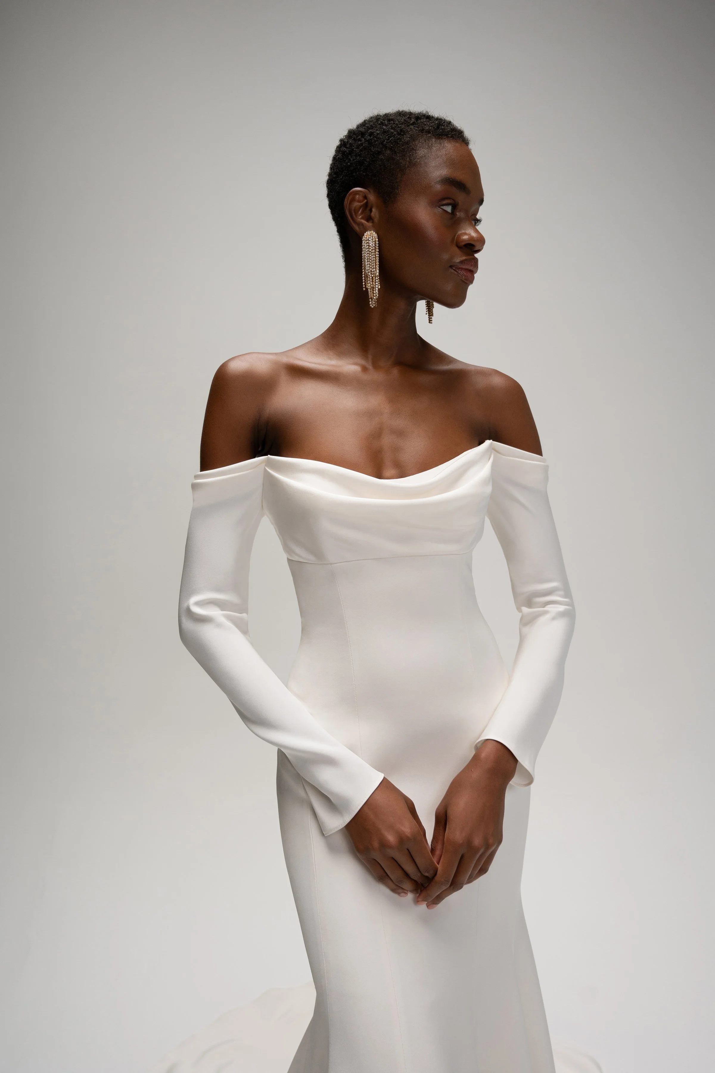 The Jenny Yoo Briar gown is a sophisticated fit-and-flare bridal dress in lustrous silk crepe with a softly draped empire bodice that flatters the décolletage and highlights the shoulders. It features long, slim sleeves and an off-the-shoulder or ele