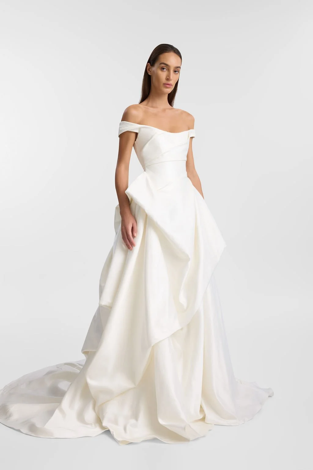 Cool girls wear KYHA Bride Willis. Luxe ivory silk satin is directionally draped across the front bodice and crafted into architectural side folds in a celebration of the female form. A full draped skirt and a sweeping train create a more-is-more sta