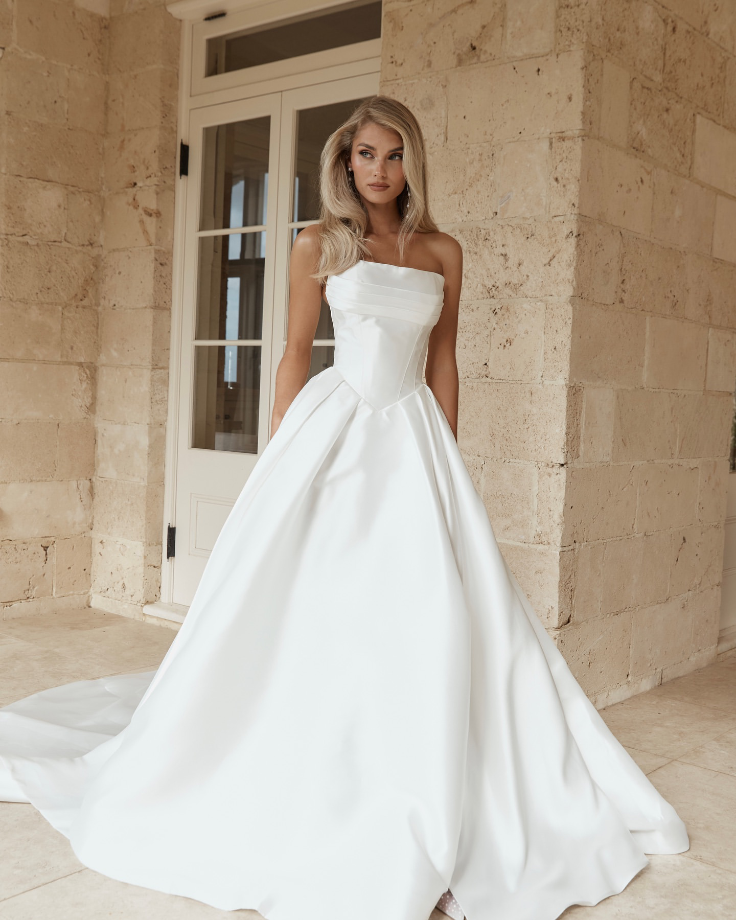 Jane Hill Bridal Anderson timeless meets modernity in Anderson. with a flattering elongated v-shaped corset and clean straight neckline, this gown is finished with our voluminous signature skirt in luxe mikado