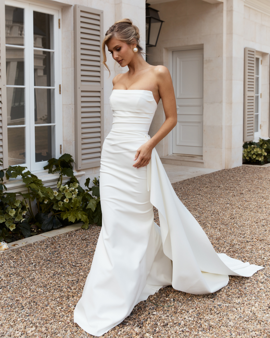 Elegant and effortlessly modern, Jane Hill Bridal Eastwood features a clean straight neckline and a beautifully fitted silhouette that skims the body with simplicity. Soft ruching through the bodice adds subtle texture and shape, creating a flatterin