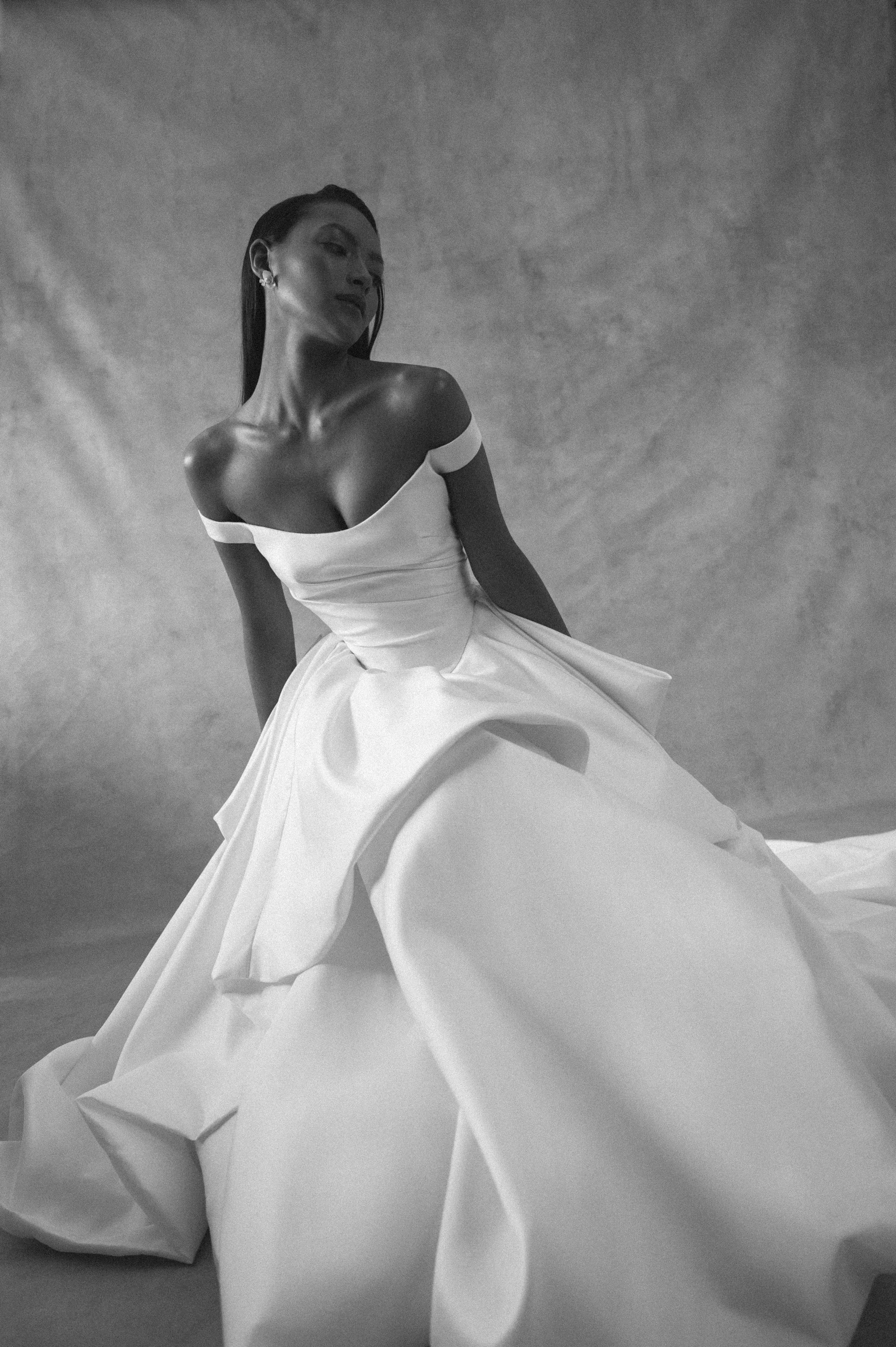The Jenny Yoo Bridal Elle gown, cut in our lofty Italian taffeta, is a true chameleon. Featuring a corseted bodice with a flattering Basque waist and a delicate off the shoulder strap, her voluminous skirt transforms into a dramatic high-low look per