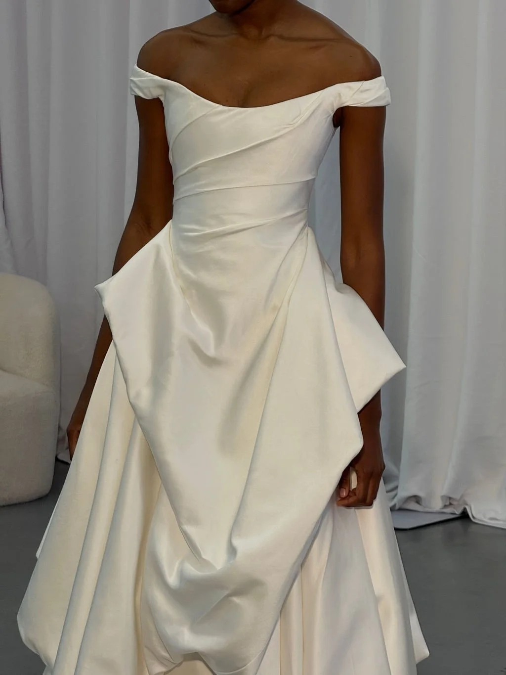Cool girls wear KYHA Bride Willis. Luxe ivory silk satin is directionally draped across the front bodice and crafted into architectural side folds in a celebration of the female form. A full draped skirt and a sweeping train create a more-is-more sta