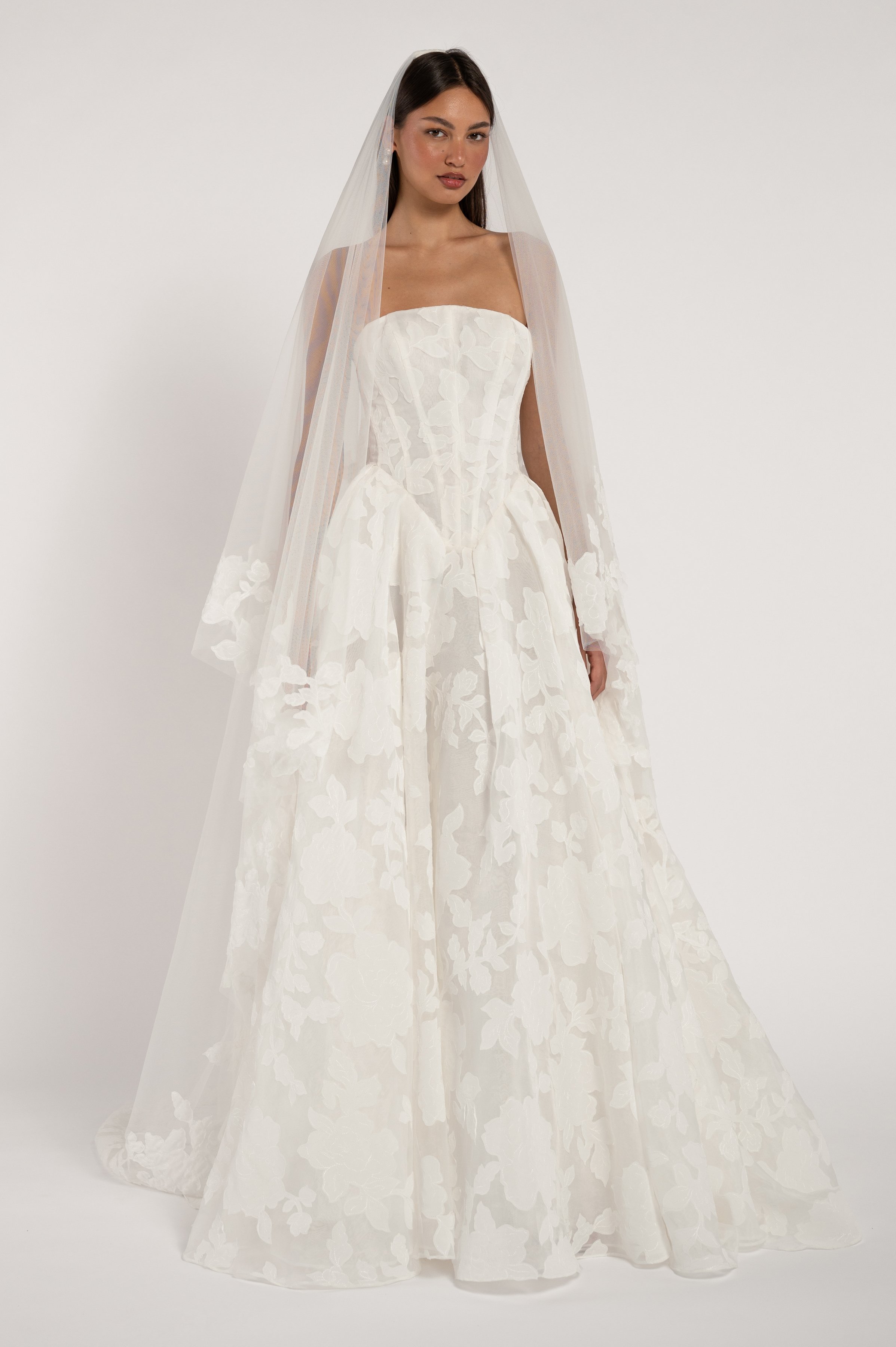 Jenny Yoo The Alva gown marries a modern corset bodice with a dramatically romantic floral motif. The overall effect being one that is strikingly timeless. Available at Halo & Wren