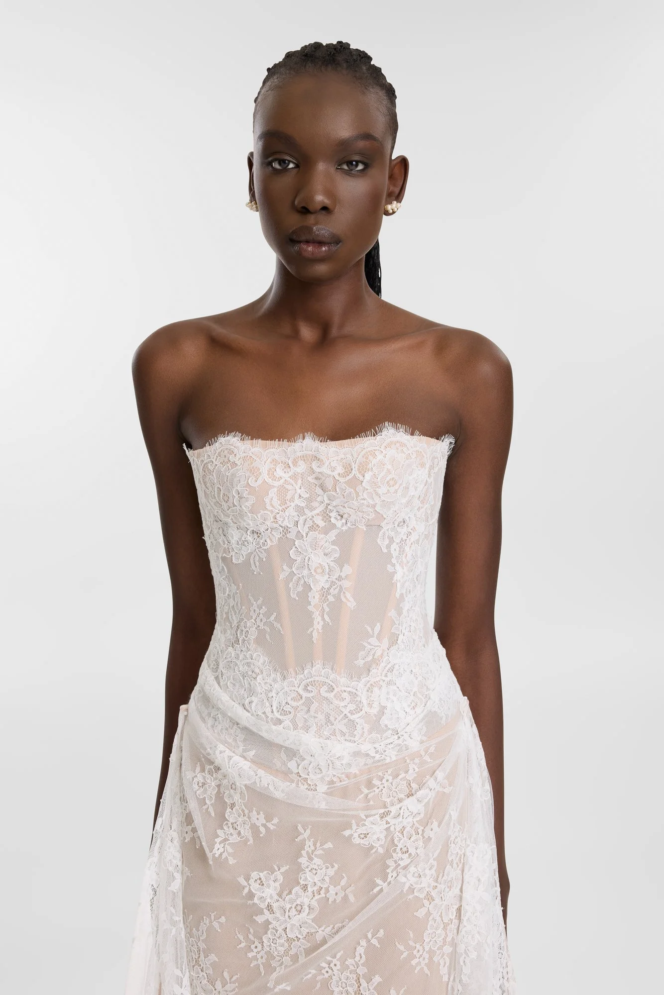 Diaphanous dressing in KYHA Bride Wilton. Constructed by hand-moulding delicate lace, Wilton sees swathes of sheer lace contrast a nude chiffon base for a study in understated impact. A highly structured, corseted bodice boasts a scalloped edge along