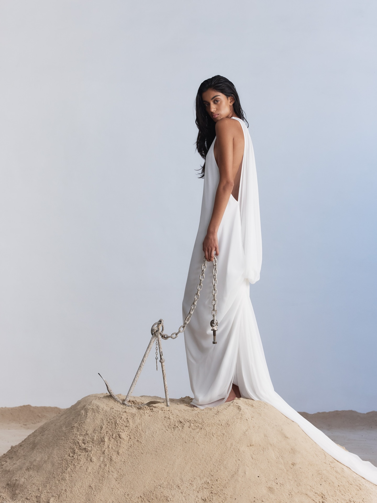 Floating on Air(eys). Rethinking the code of tradition, Aireys is defined by movement thanks to its open draped back that falls away from the body, gathering in a dramatic knot and extending into a train that descends from the knot into a soft puddle