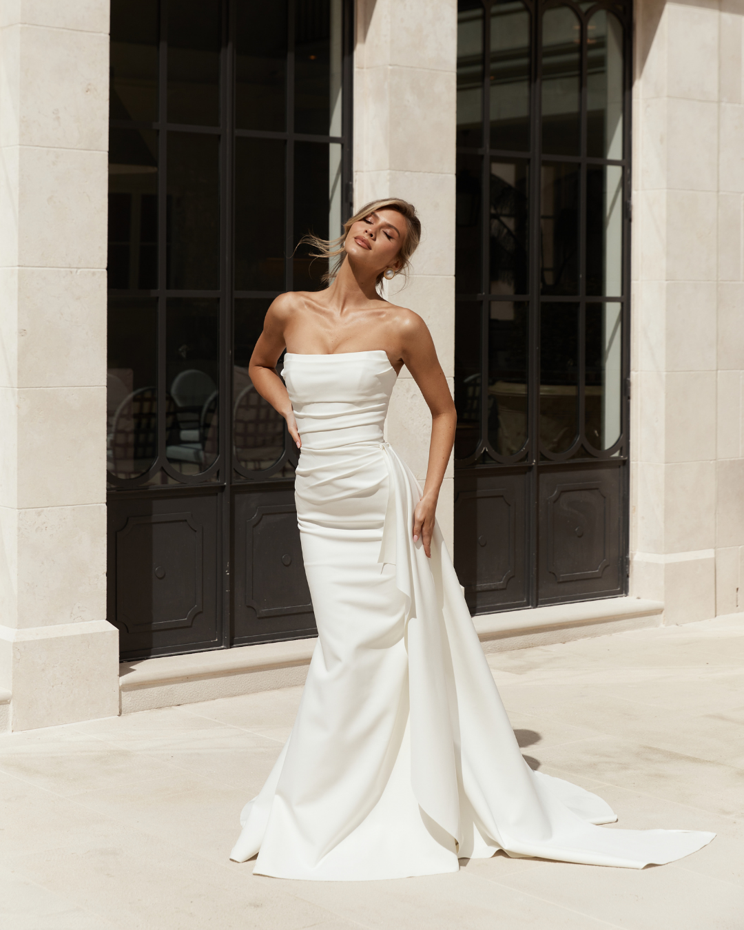 Elegant and effortlessly modern, Jane Hill Bridal Eastwood features a clean straight neckline and a beautifully fitted silhouette that skims the body with simplicity. Soft ruching through the bodice adds subtle texture and shape, creating a flatterin