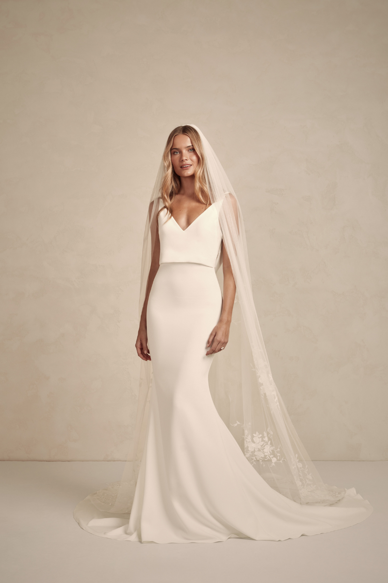 Austin offers a modern twist on a classic MWL design, combining the best elements into one timeless, flattering crepe dress. This elegant yet alluring gown features a delicate drape at the waist, enhancing its sleek, figure-hugging silhouette.